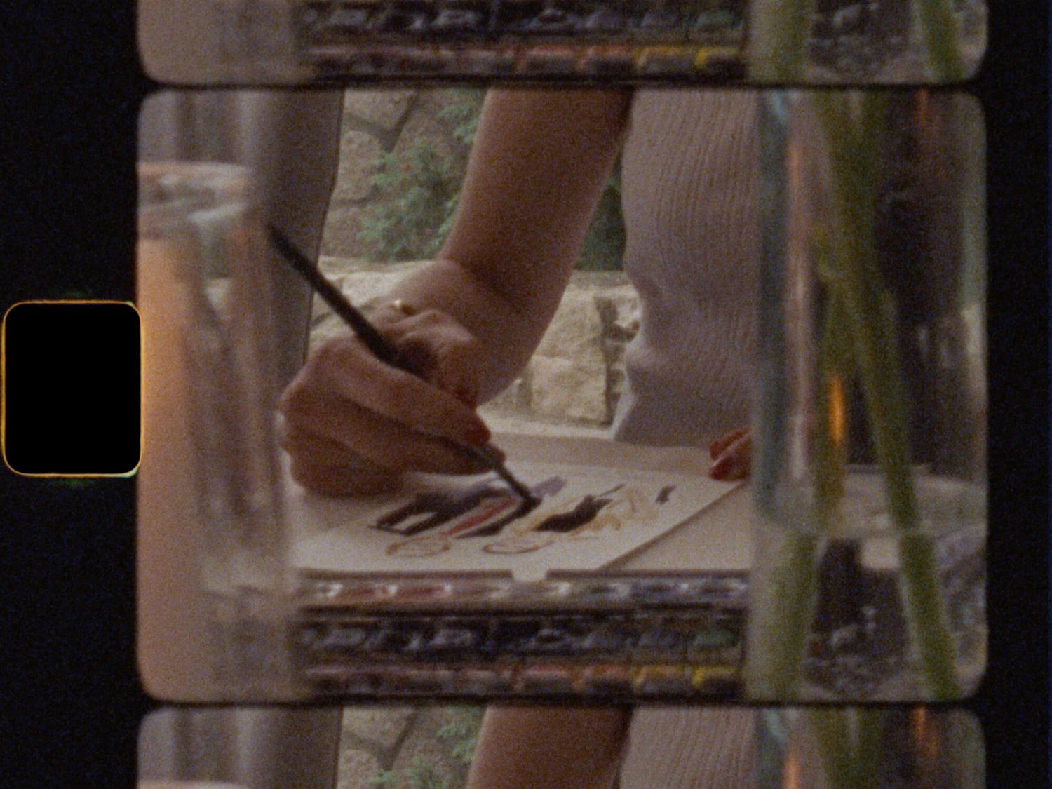 Artist painting at a window-lit art desk at Cambridge Mill in Cambridge, Ontario, captured on Super 8 wedding film.