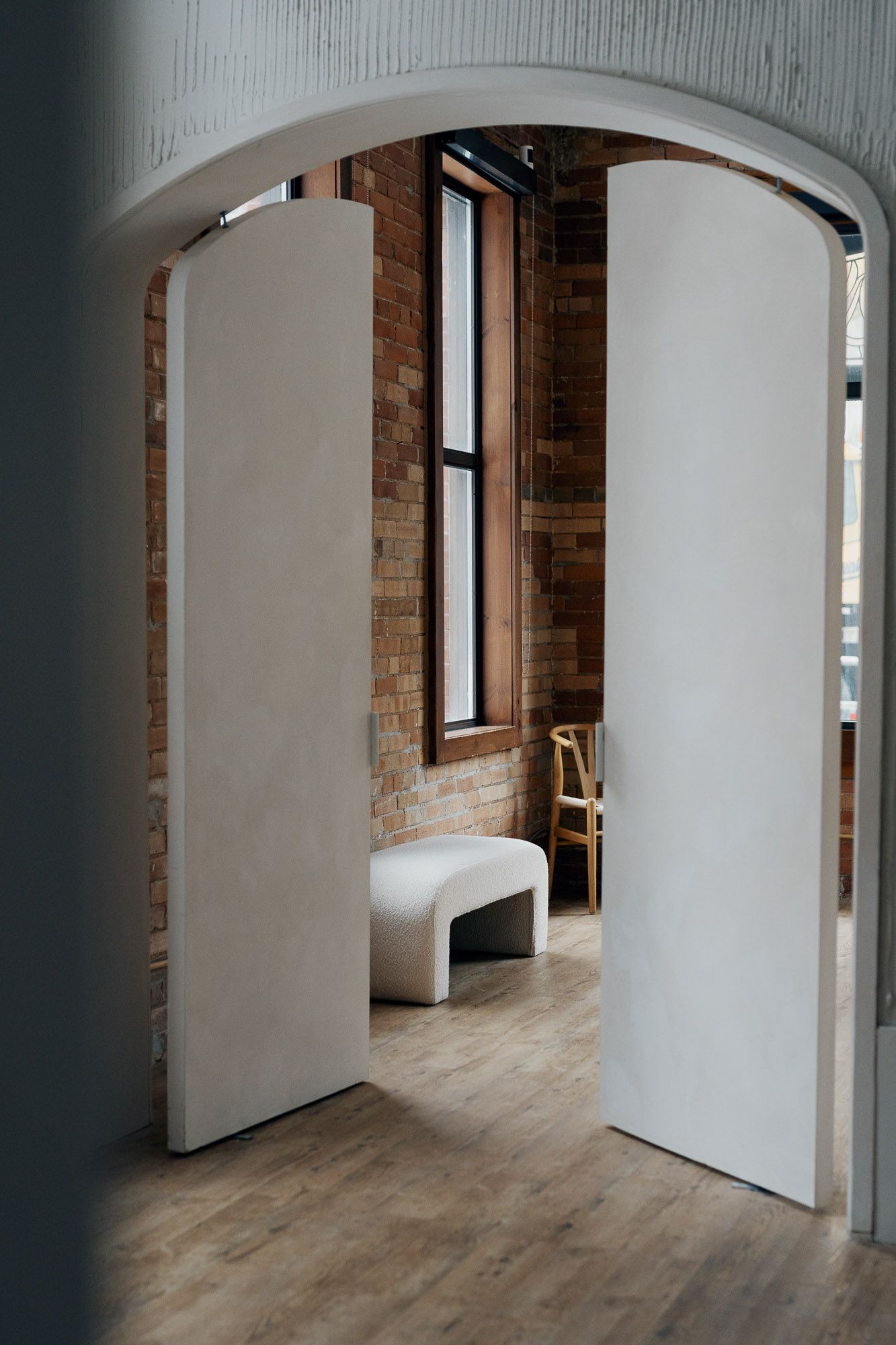 White arched doors opening to exposed brick and wood floors at Archive Studio in Toronto for intimate wedding photography.
