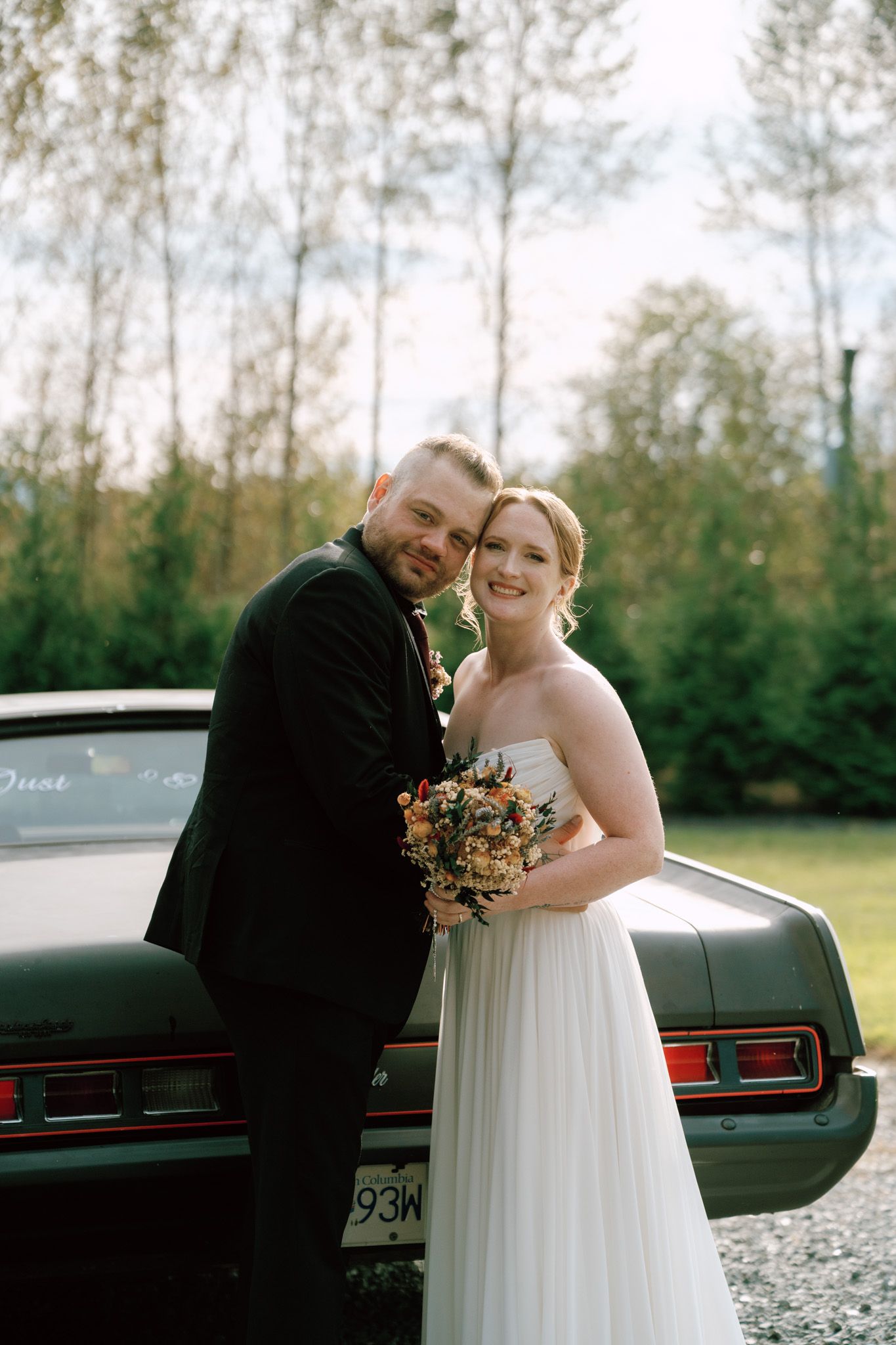 Bride and groom posing beside a vintage green car at Bridlewoods Event Center in Chilliwack, B.C. during their Vancouver wedding
