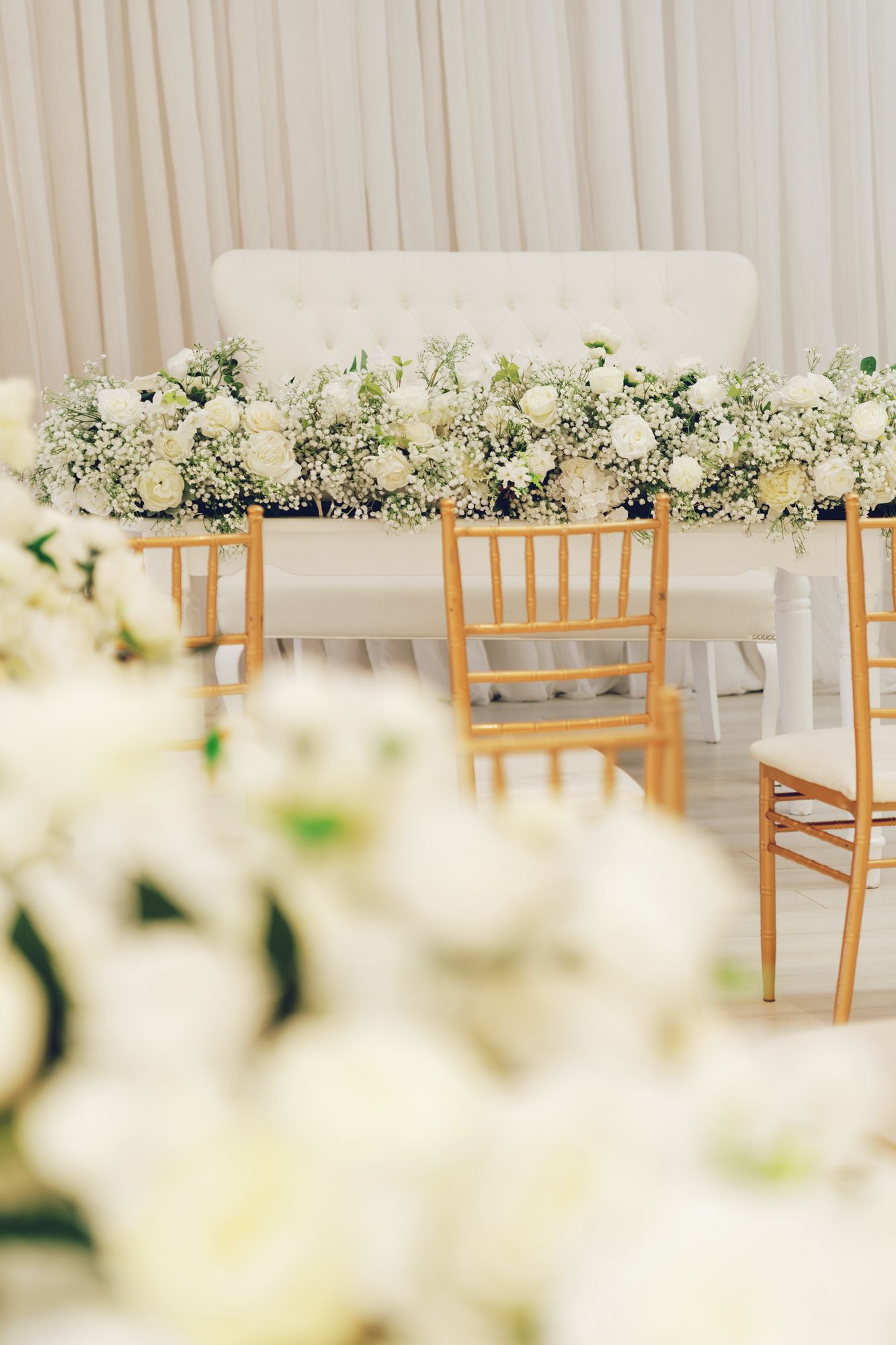 Elegant Bellamy Loft wedding reception with gold Chiavari chairs, white florals, and tufted sofa backdrop in North York, Toronto.