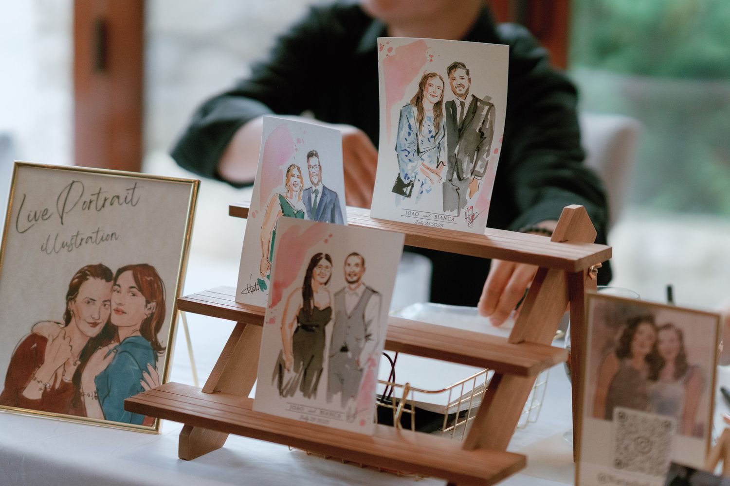 Watercolor guest portrait illustrations on a wooden easel at Cambridge Mill in Cambridge, Ontario wedding reception.