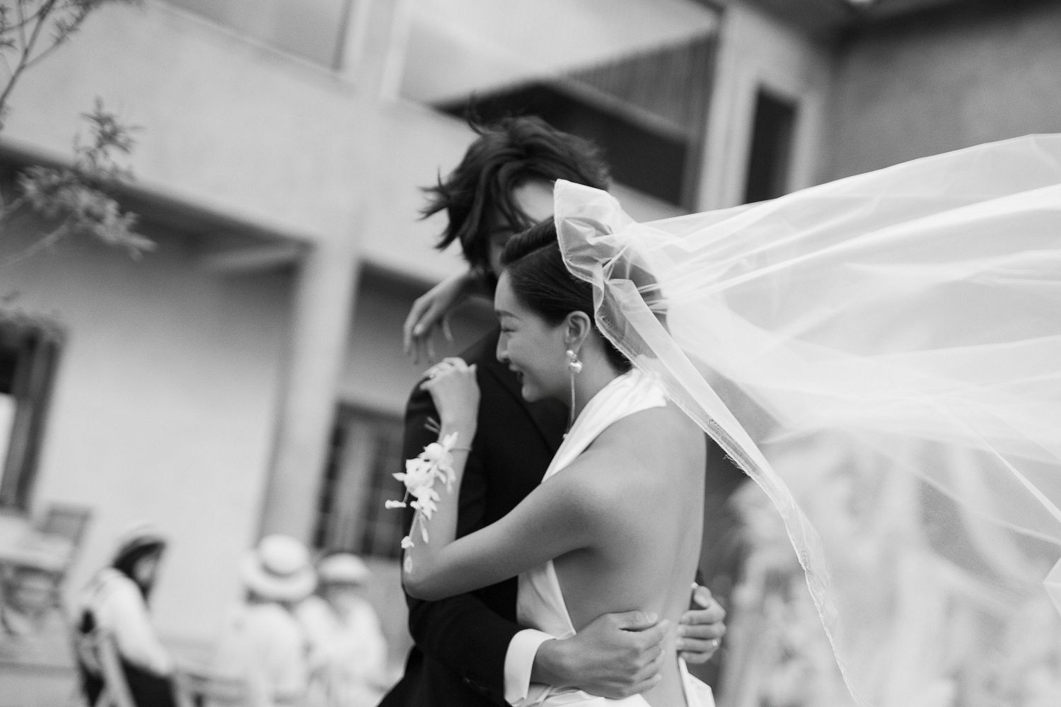 Black and white bride embracing guests in a flowing veil during an outdoor Toronto wedding celebration for candid wedding photography
