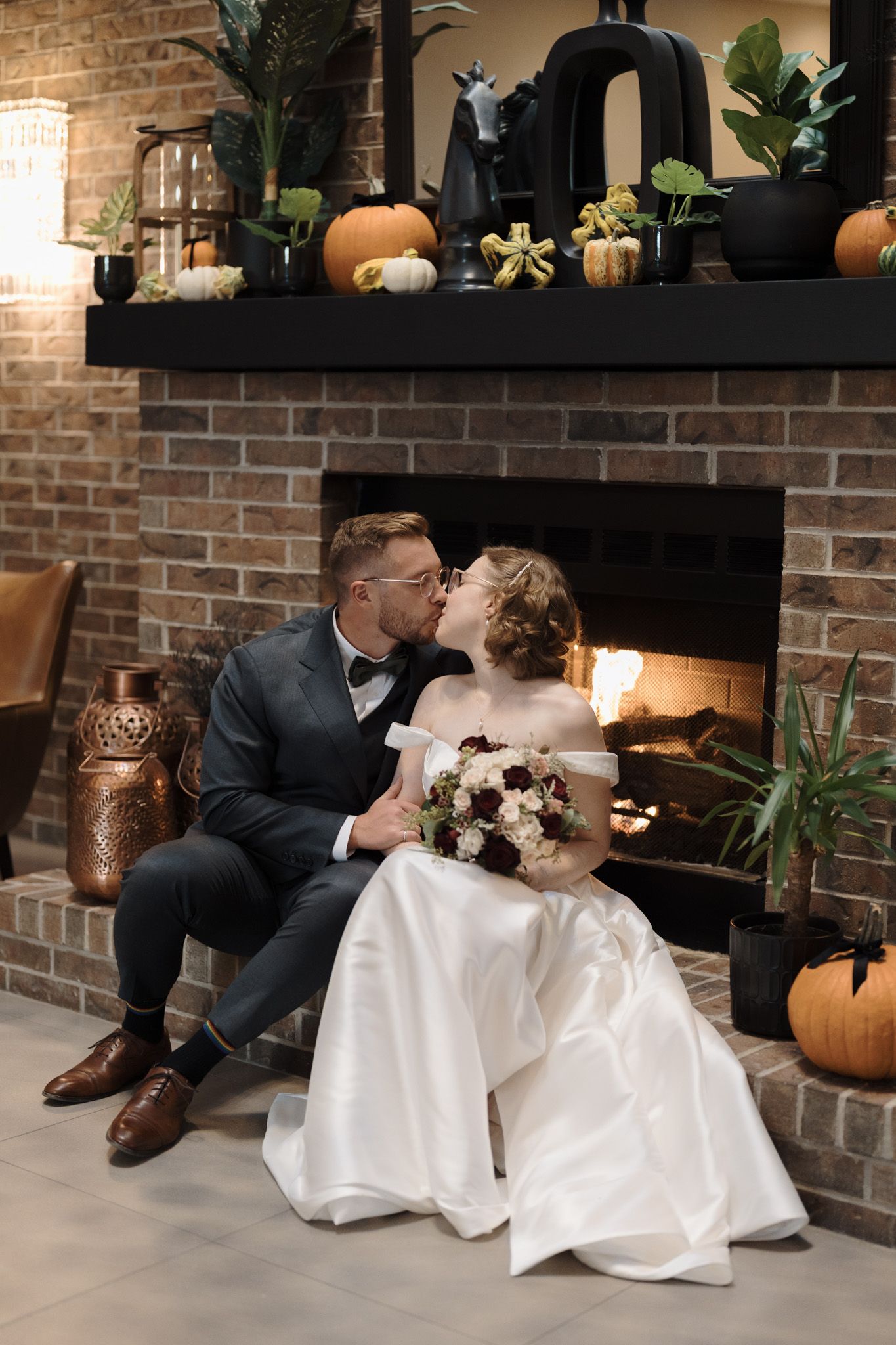 Bride and groom kissing by a decorated fireplace at The Manor in King City during their Jewish fall wedding portraits