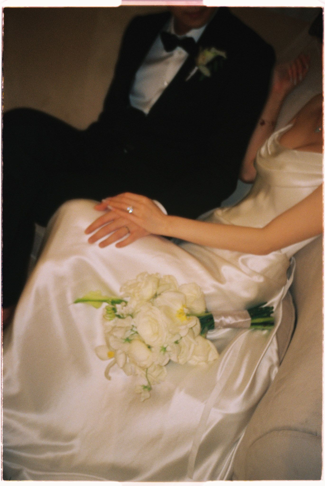 Film editorial wedding portrait of bride and groom inside a car, highlighting their attire, white rose bouquet, and ring. Toronto Photograph