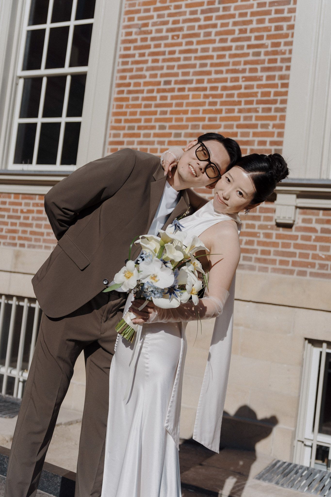 Bride with bouquet and groom in brown suit outside Osgoode Hall for Toronto City Hall wedding photography portraits.