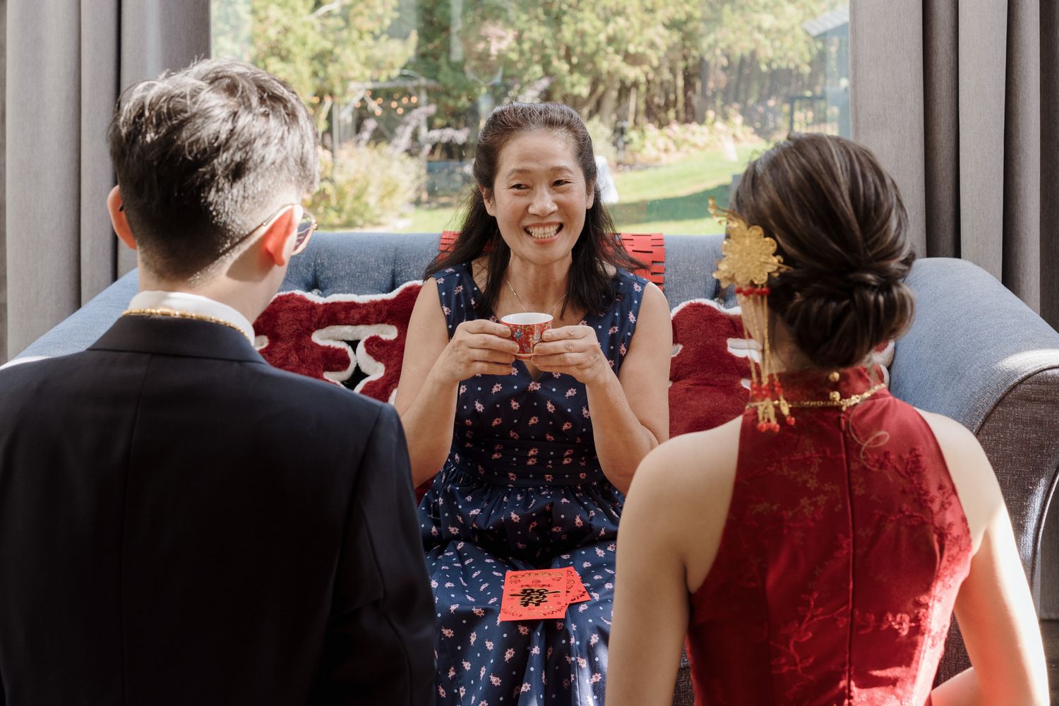 Woman in floral dress receiving tea from a couple during a Chinese tea ceremony at Razi Estate in Schomberg.