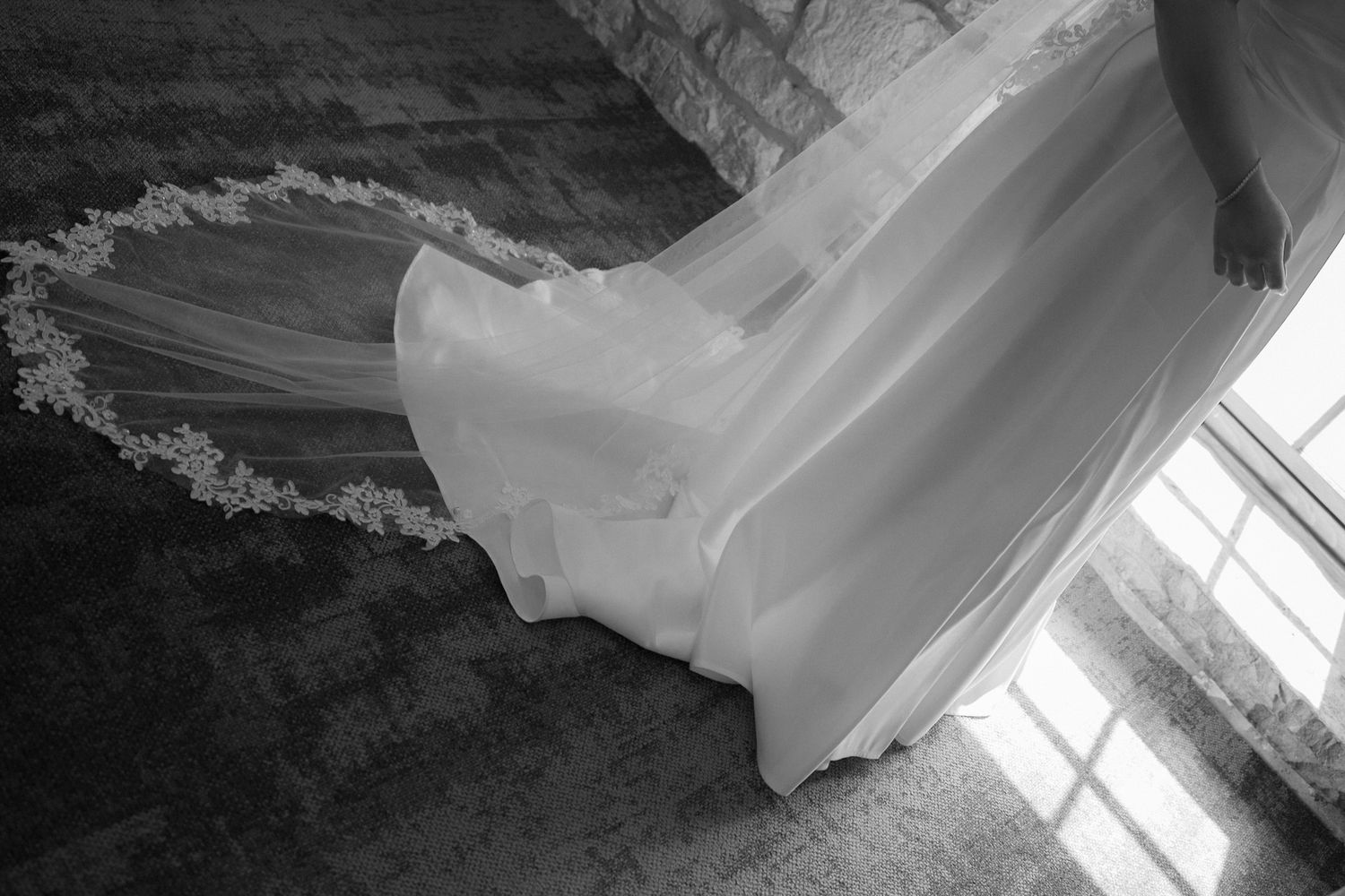 Black and white bride with lace-trimmed veil trailing on the stairs at Cambridge Mill for timeless wedding photography.