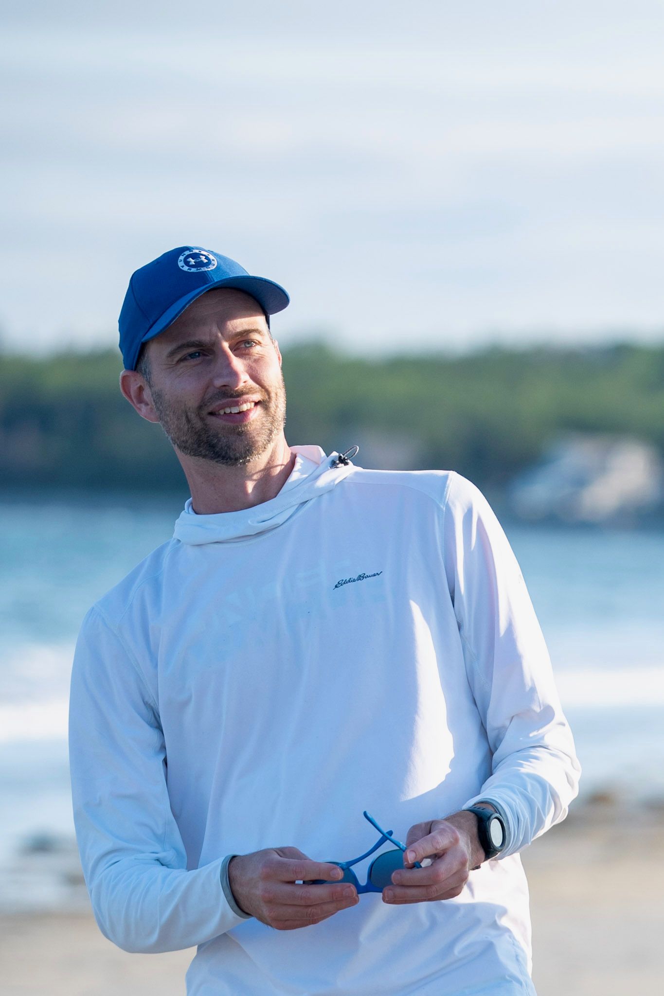 Freakishly tall Guy looking borderline viewable  on a Beach in Canada leaning back a little.