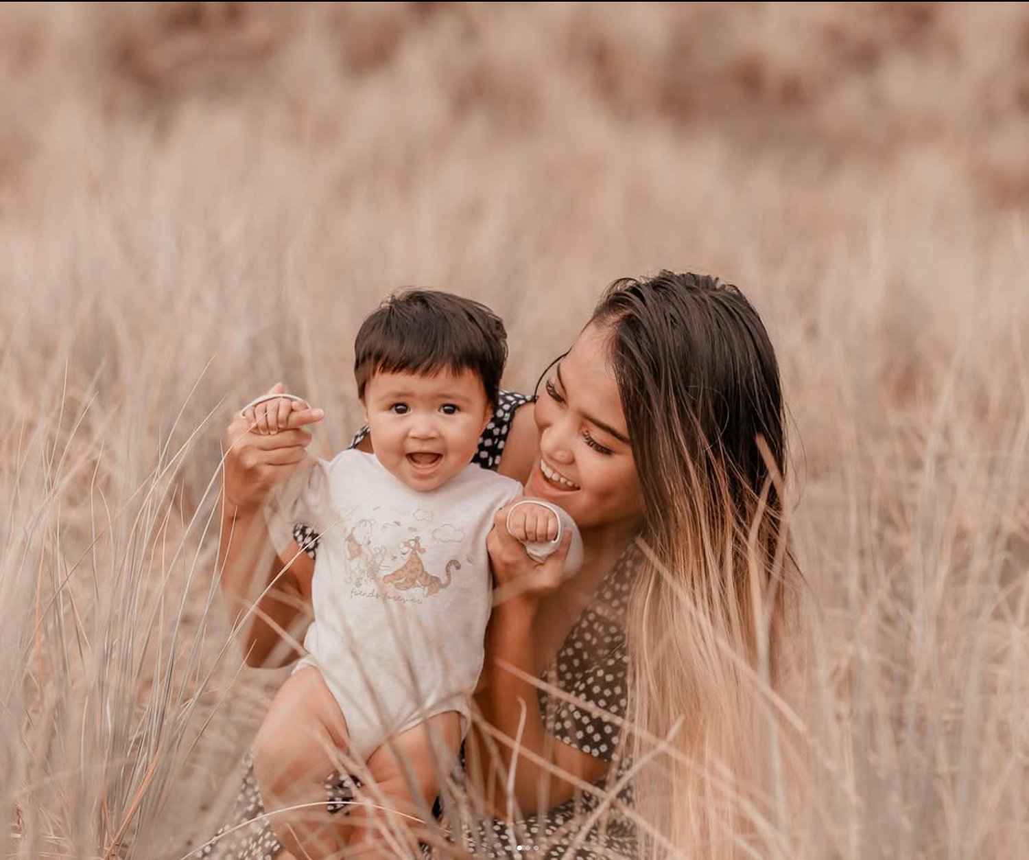 Toddler girl playing in the long grass during a golden hour family session.