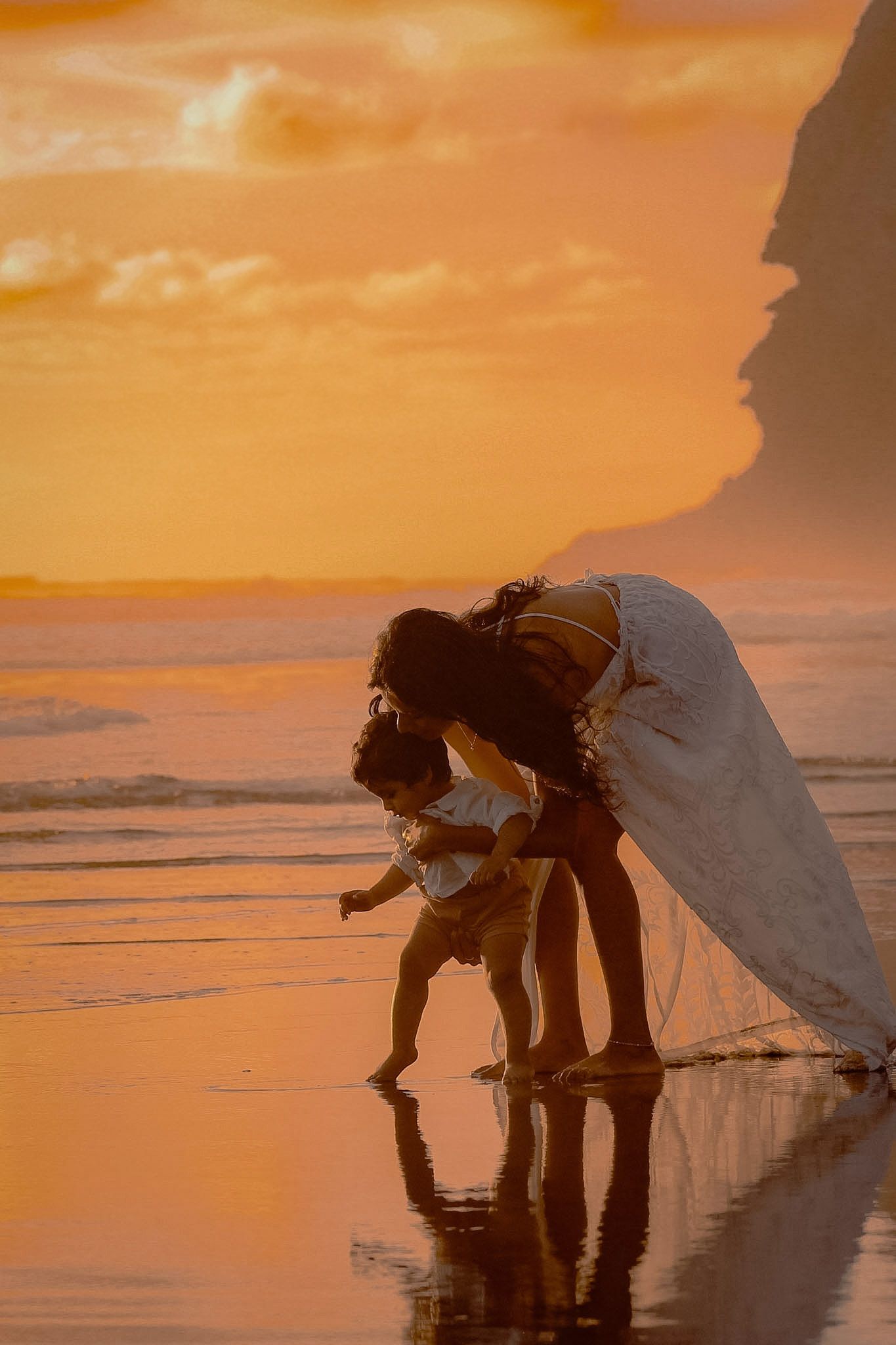 Beautiful vibrant golden sunset at the beach at Piha, as toddler learns to take first steps.