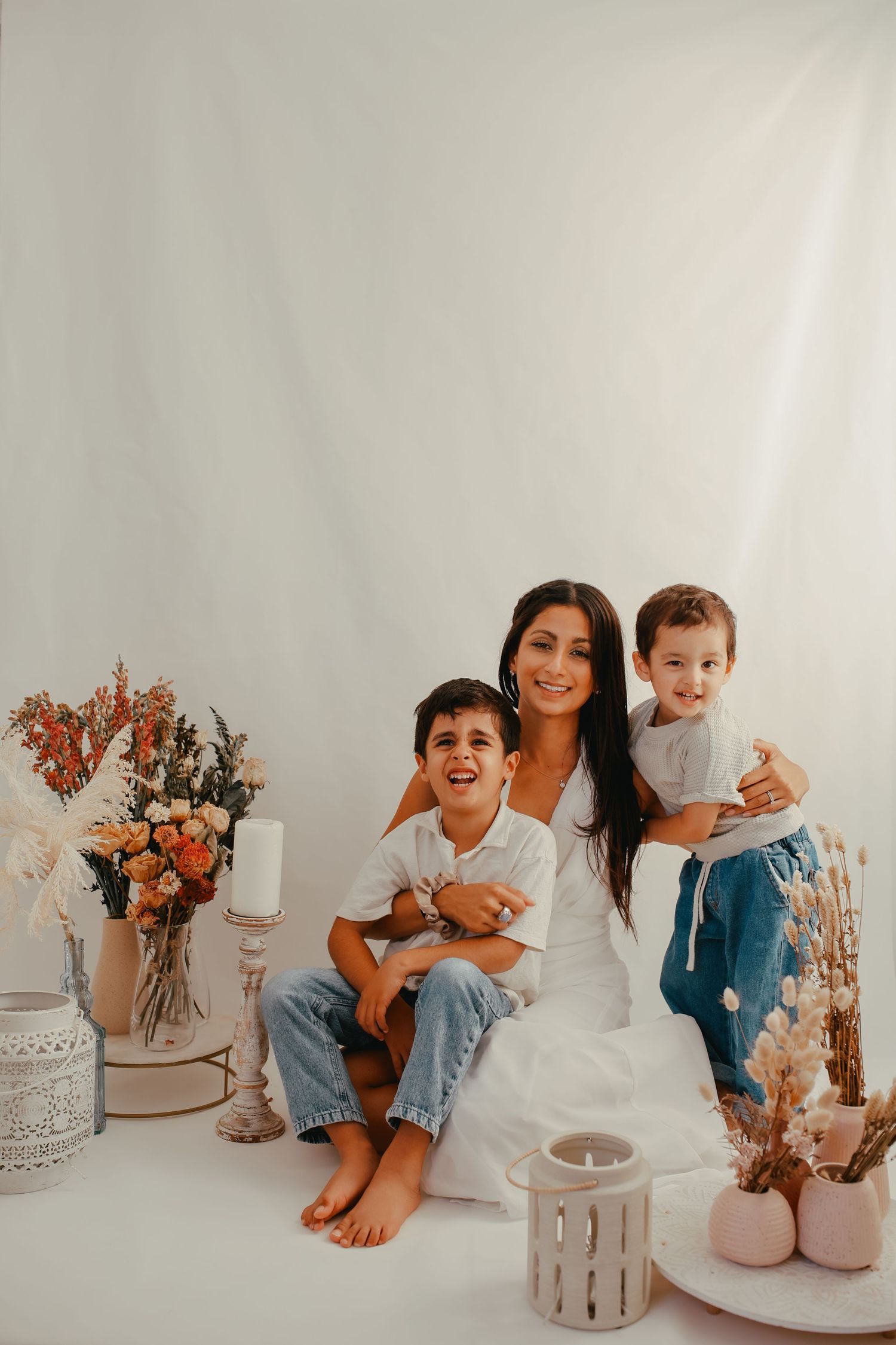 Close-up of a mother hugging her children in a studio filled with flowers.
