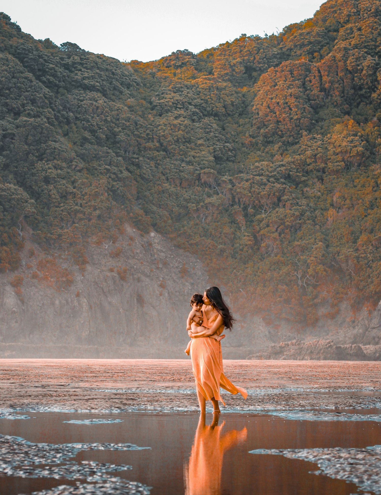 Creative photo composition with the New Zealand forest and tress as mum holds baby.