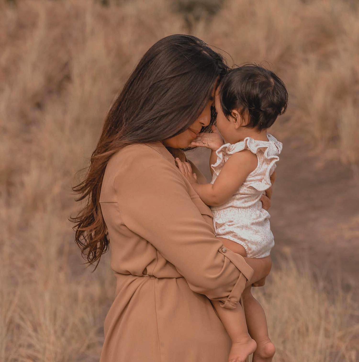 Family session at Piha during sunset. With baby girl touch mums face