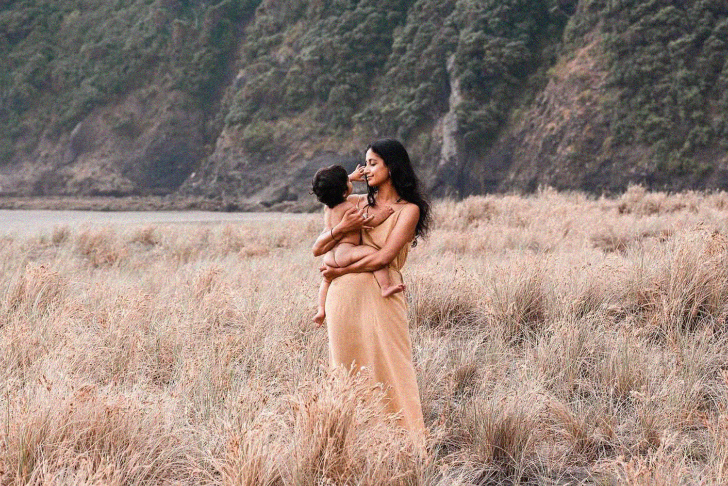 Soft-focus portrait of a mother and child in a meadow.