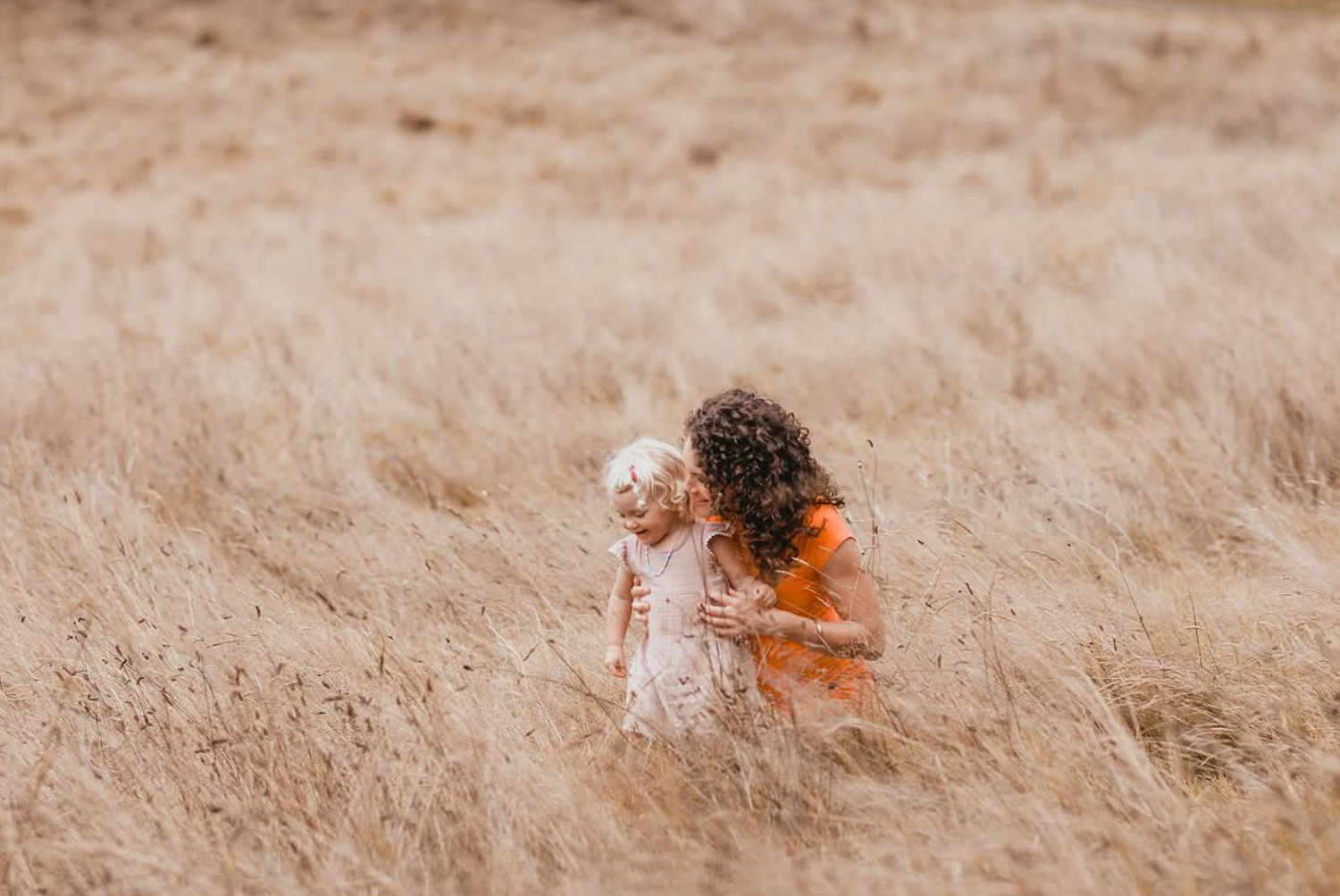 Maternity photo of a woman in a flowing dress standing in the long grass at Cornwall Park, Epsom.