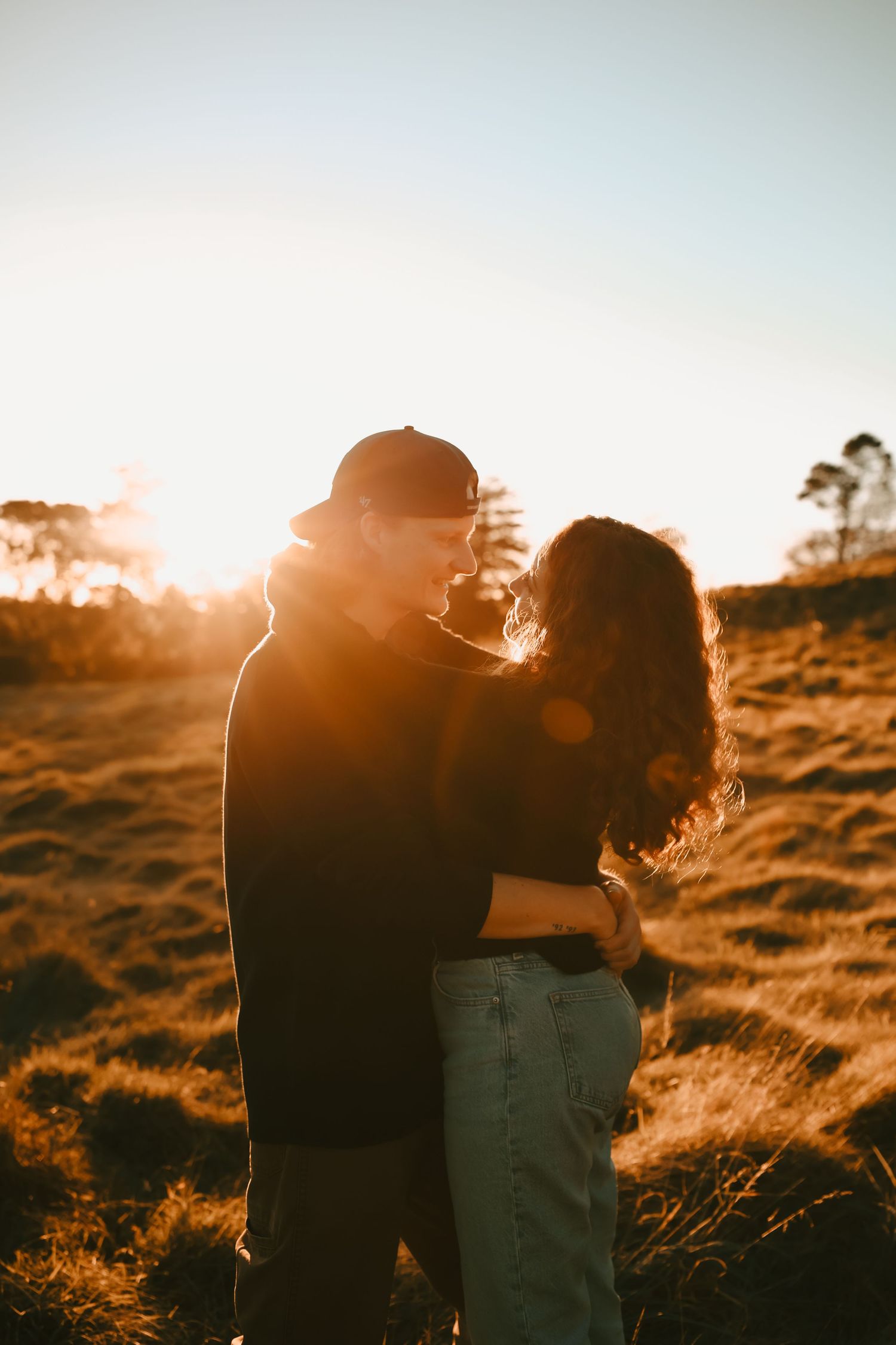 Moody and romantic engagement photo featuring warm lighting and a soft-focus background.