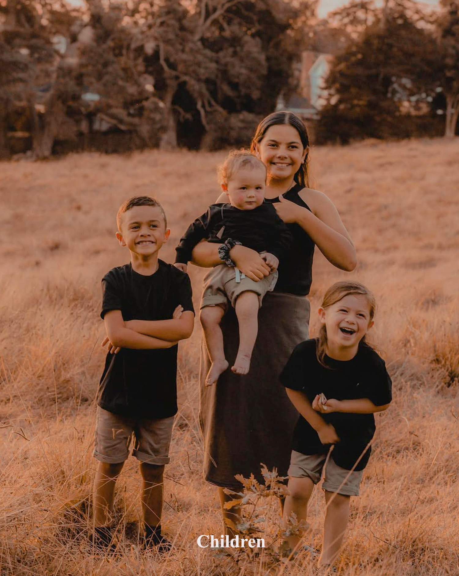 Candid portrait of siblings and children playing in a field during a sunset family photo shoot in Auckland Cornwall Park.