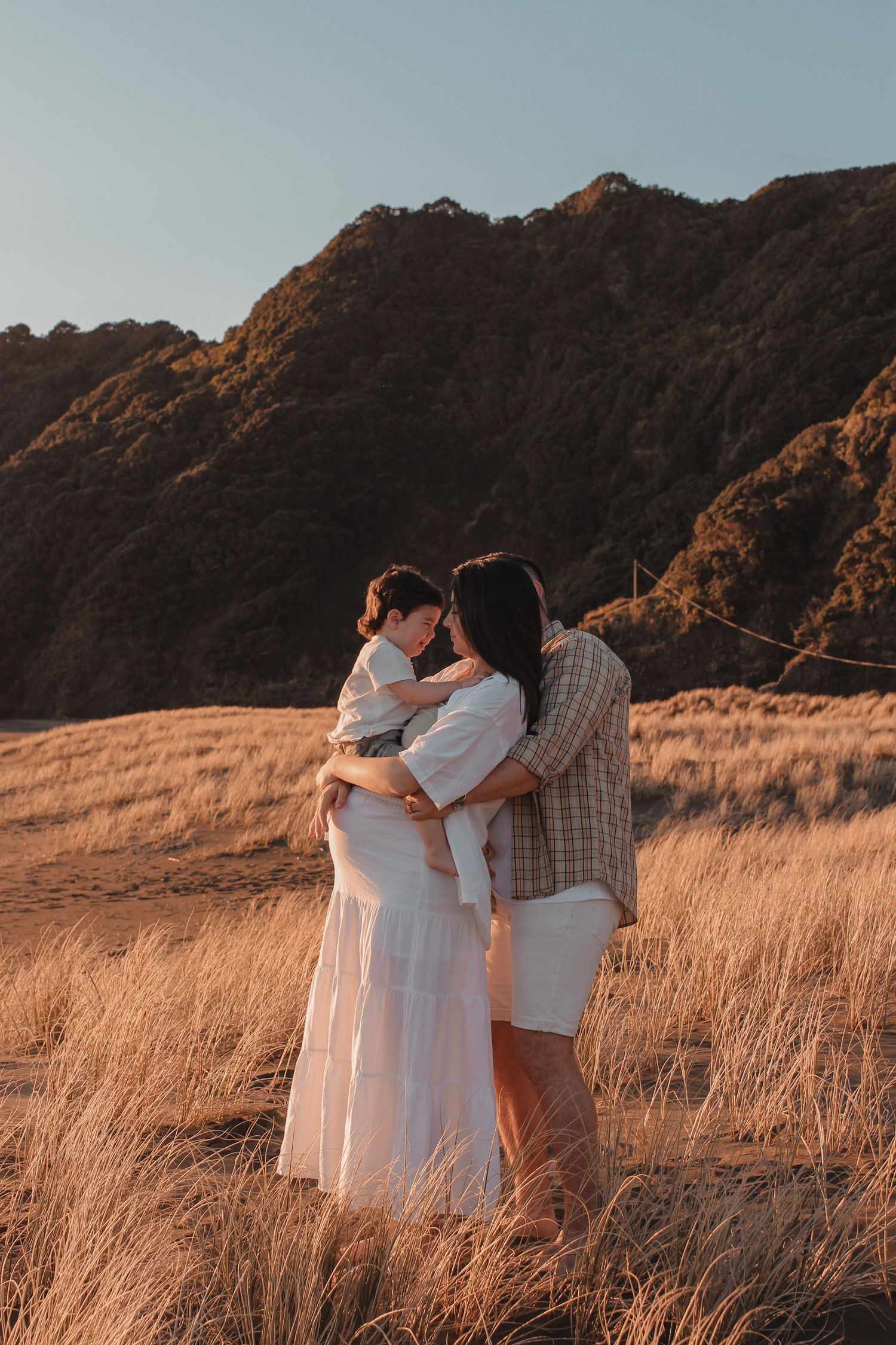Family photography session at Piha Beach during golden hour.