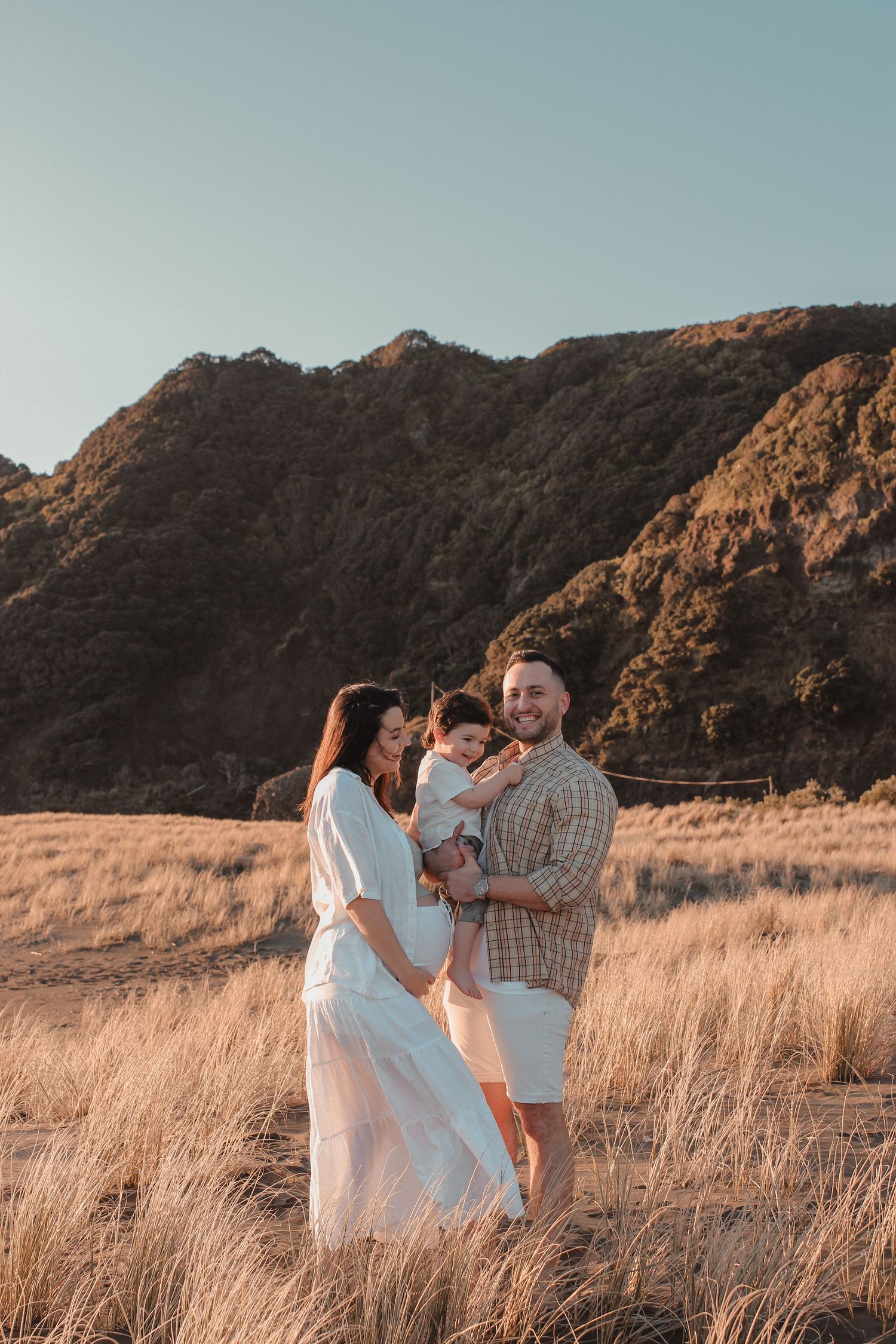 Couple embracing during Auckland beach sunset photoshoot.