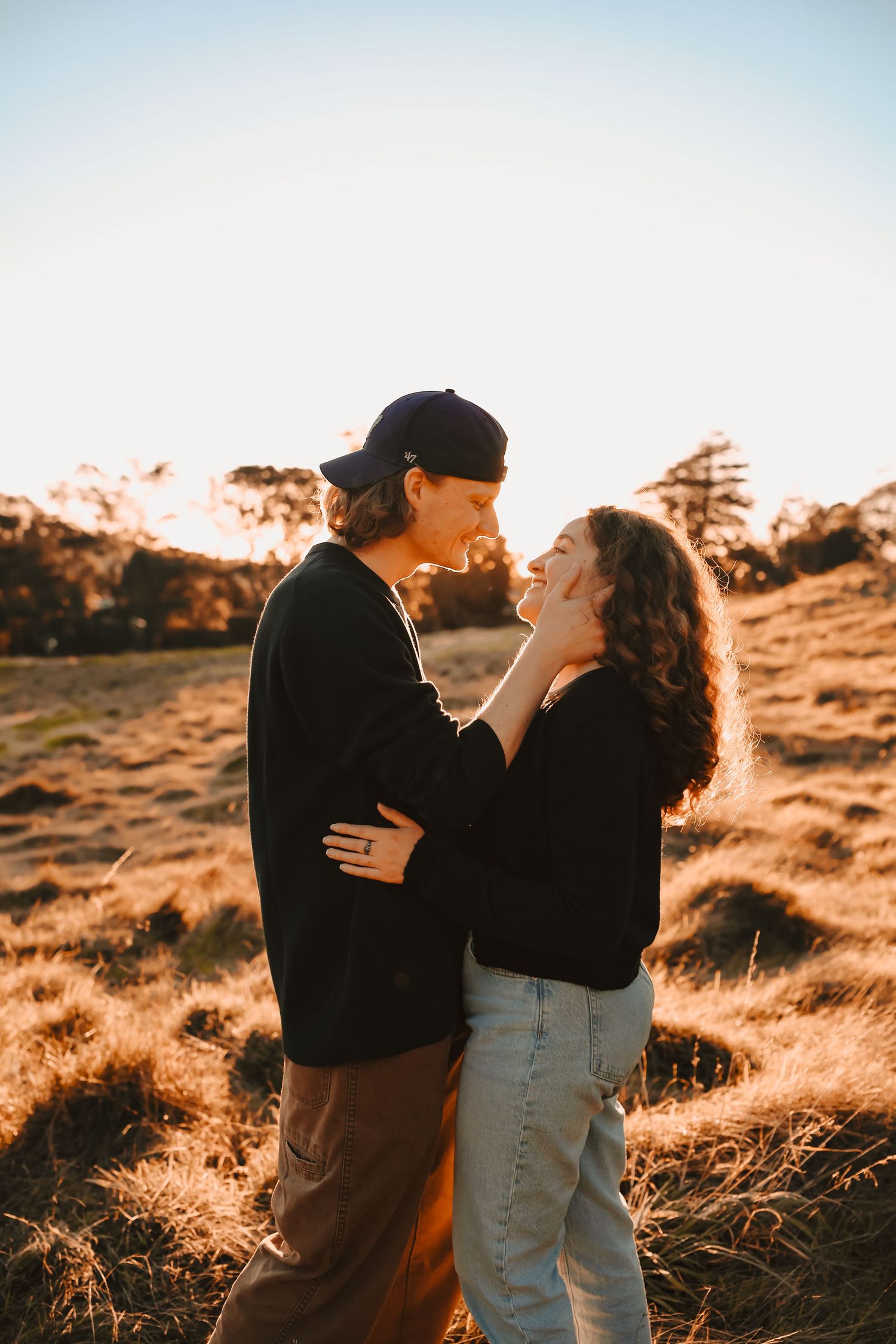 Side profile of a couple in trendy, casual streetwear sharing a romantic look outdoors.