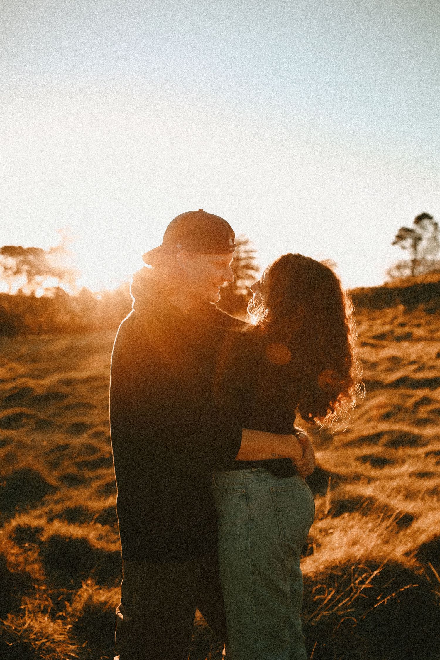 Candid outdoor couple's portrait capturing movement and warm, grainy film tones.