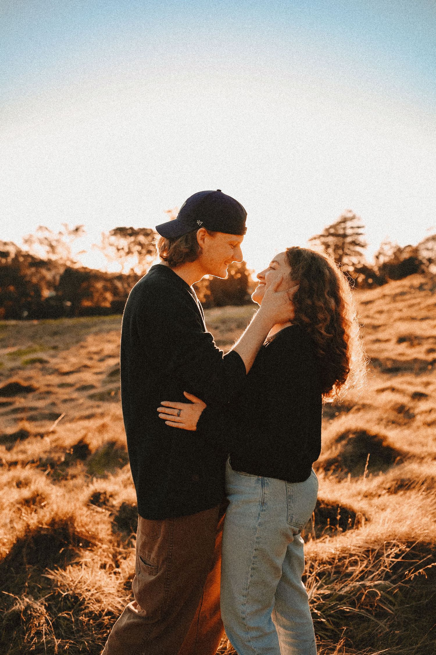 An intimate close-up of a couple looking lovingly into each other's eyes during a backyard or field sunset session.
