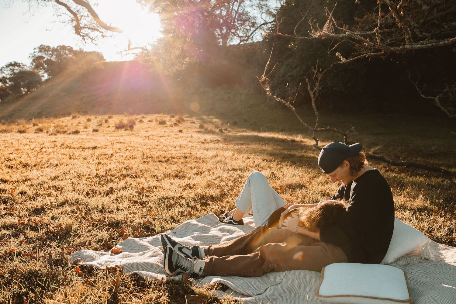 Pure joy captured as a couple laughs together while lounging on an outdoor picnic setup at dusk.