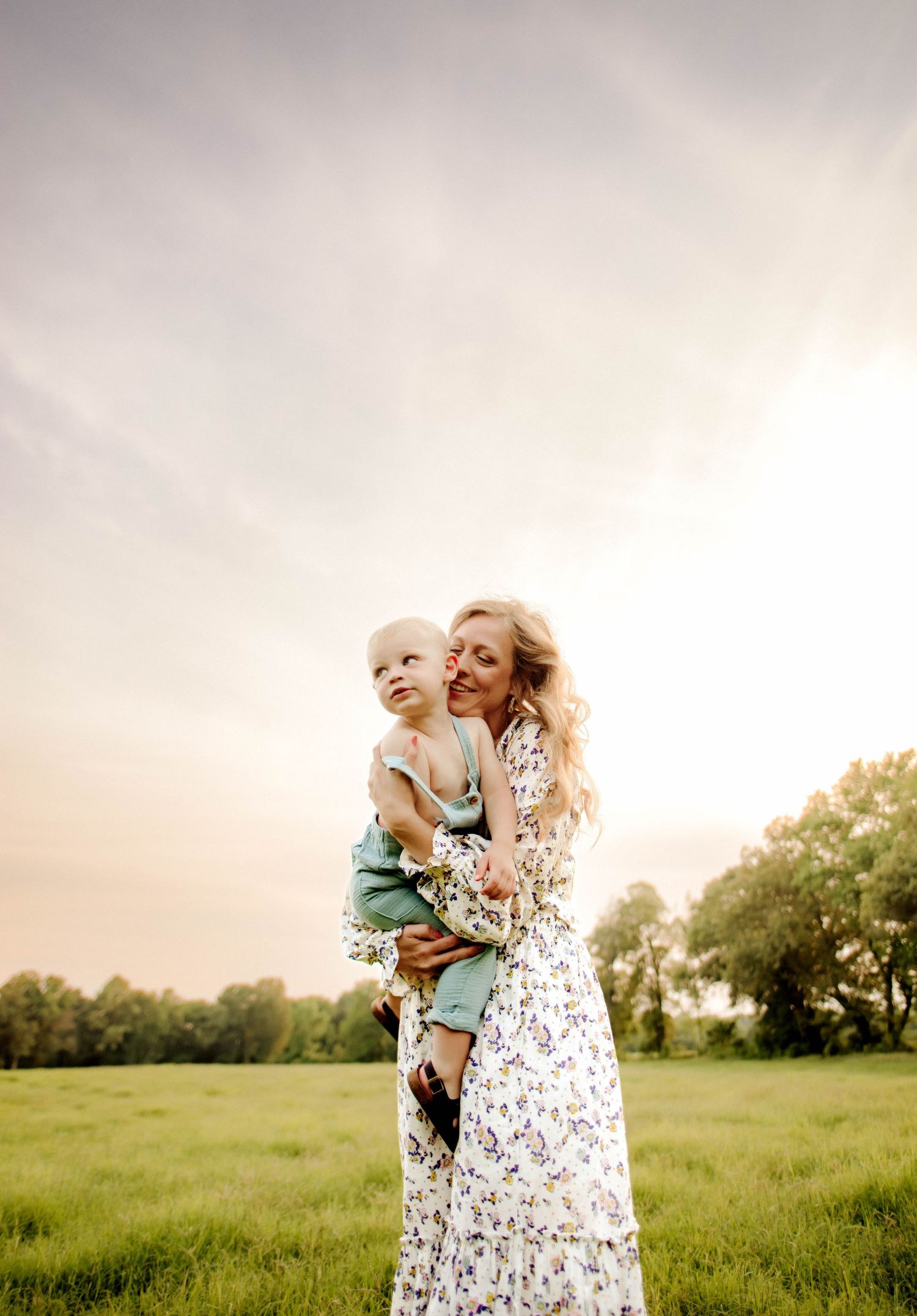 Sweet candid moment photographed in a lush green field at dusk.