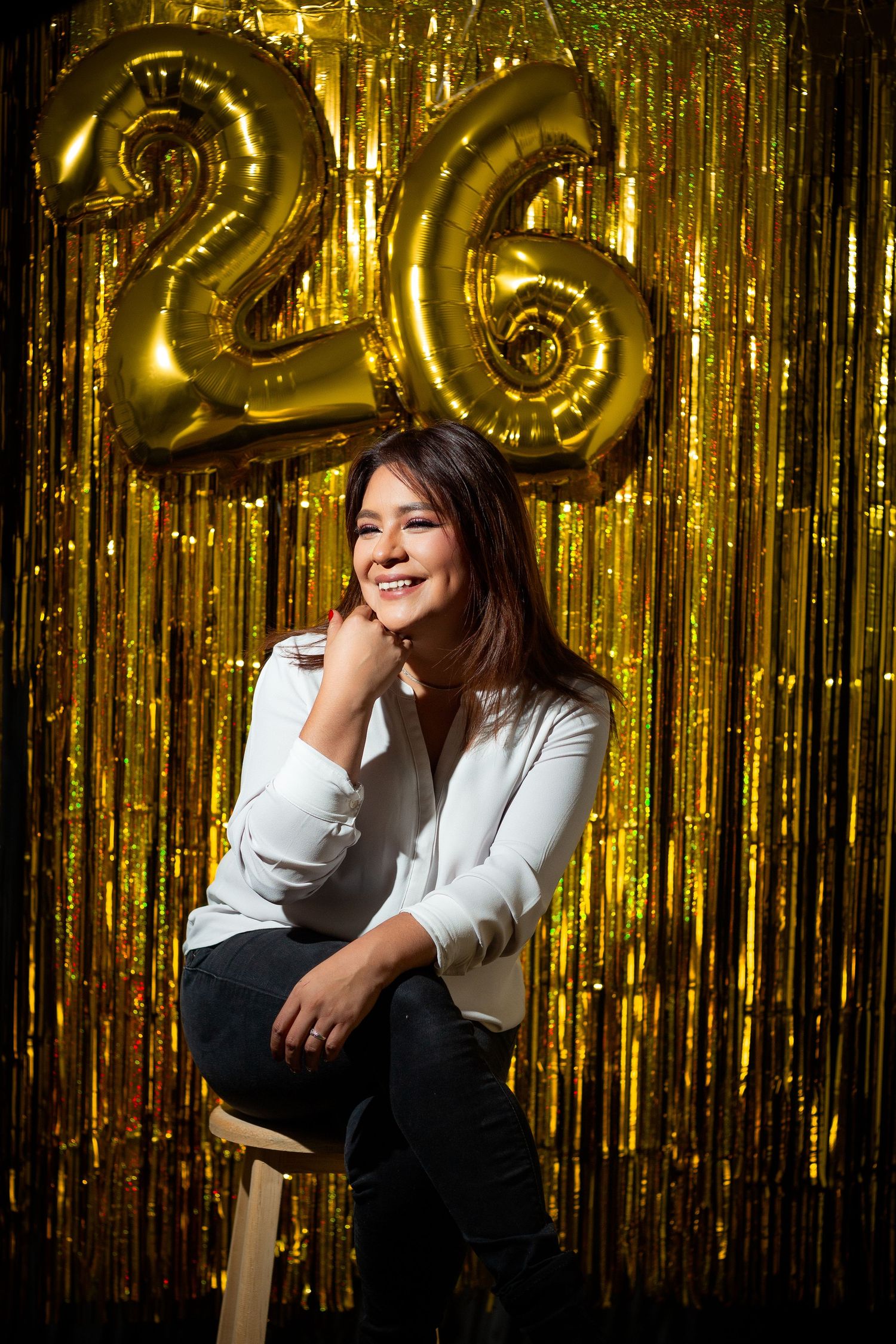 Birthday celebration with gold number 26 balloons against sparkly backdrop.