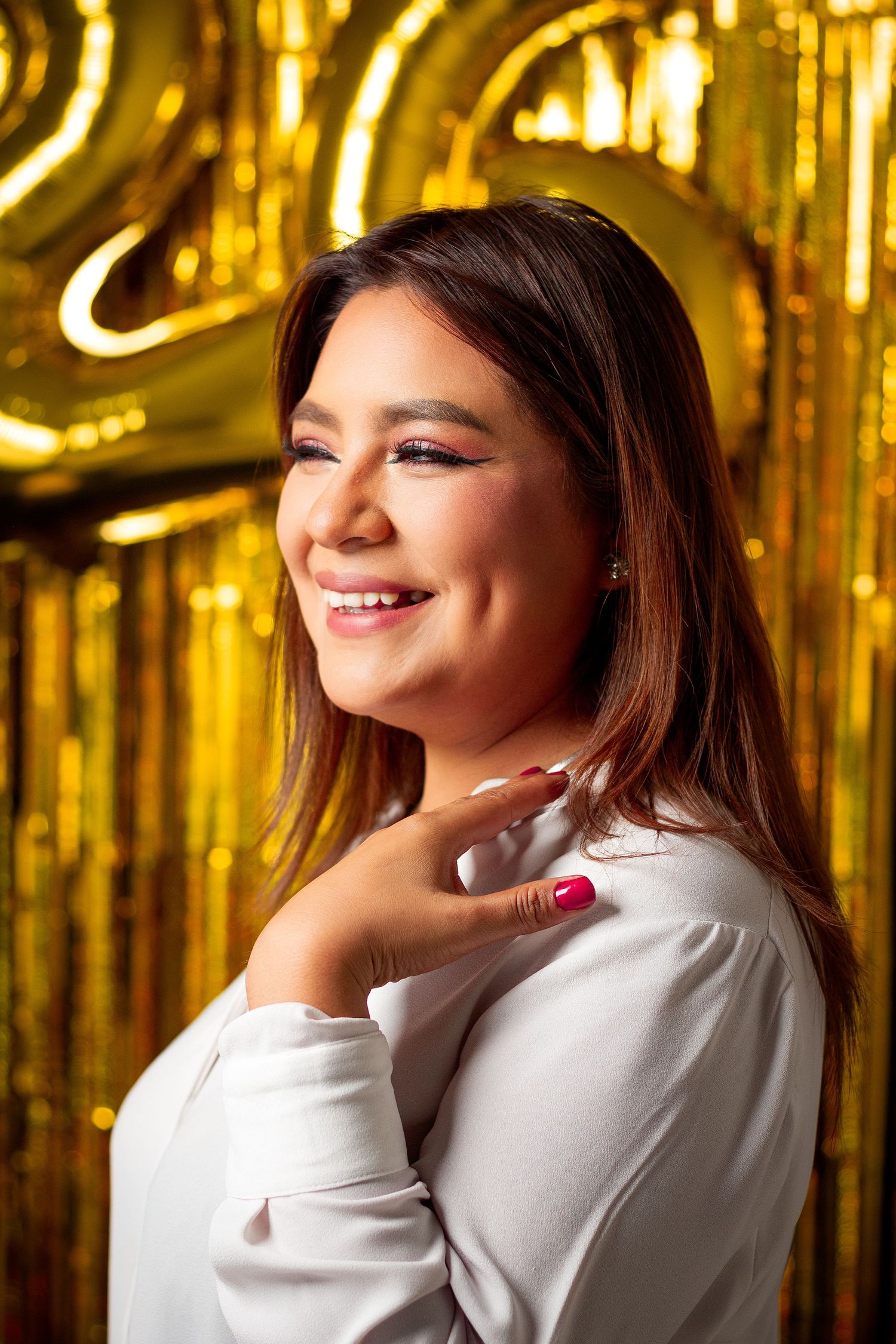 Portrait against a gold sparkly backdrop with warm lighting and elegant styling.