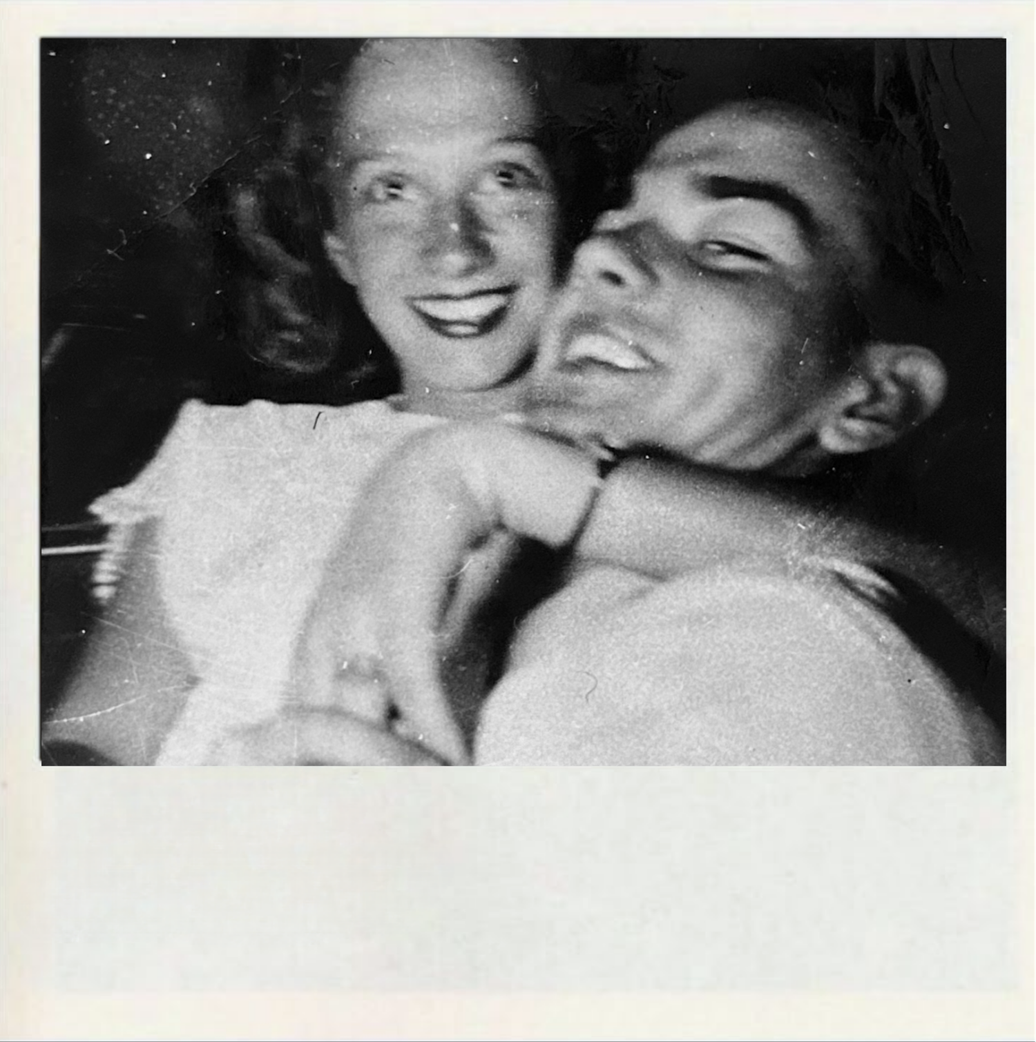 Black and white vintage photo showing a couple laughing together in an intimate candid moment.