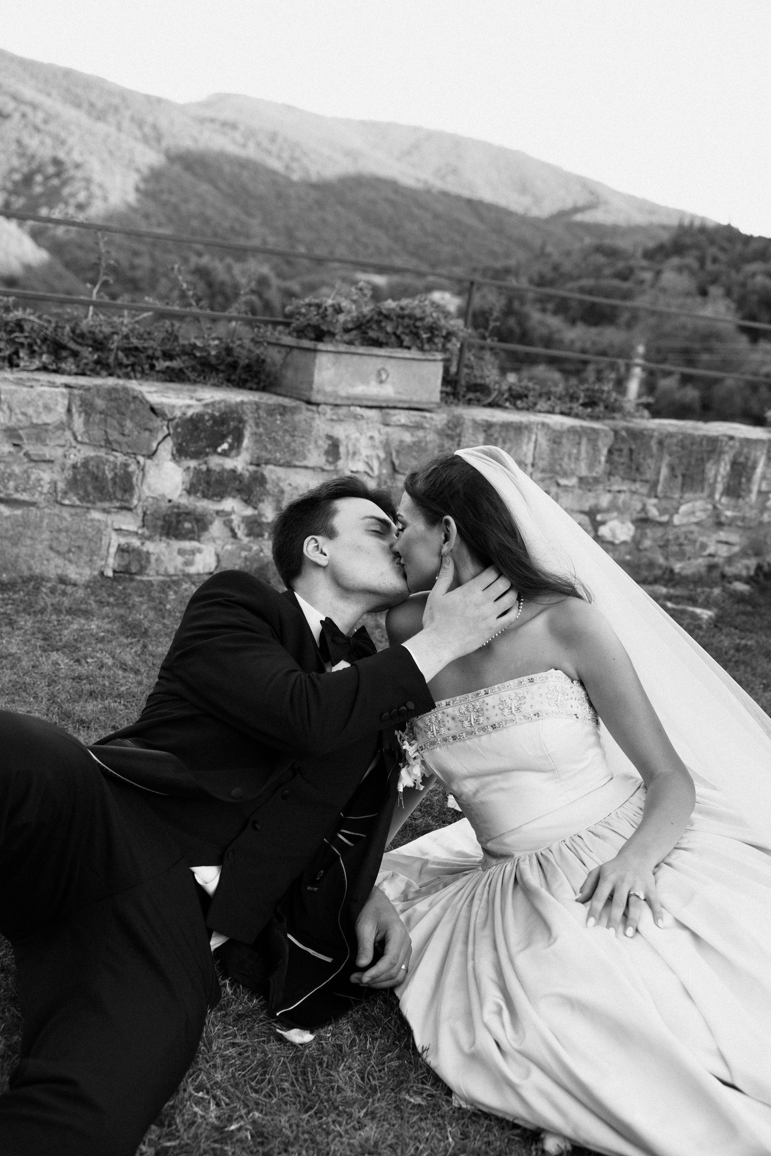 A romantic black and white wedding photo sequence showing a couple sharing tender kisses against a stone wall backdrop.