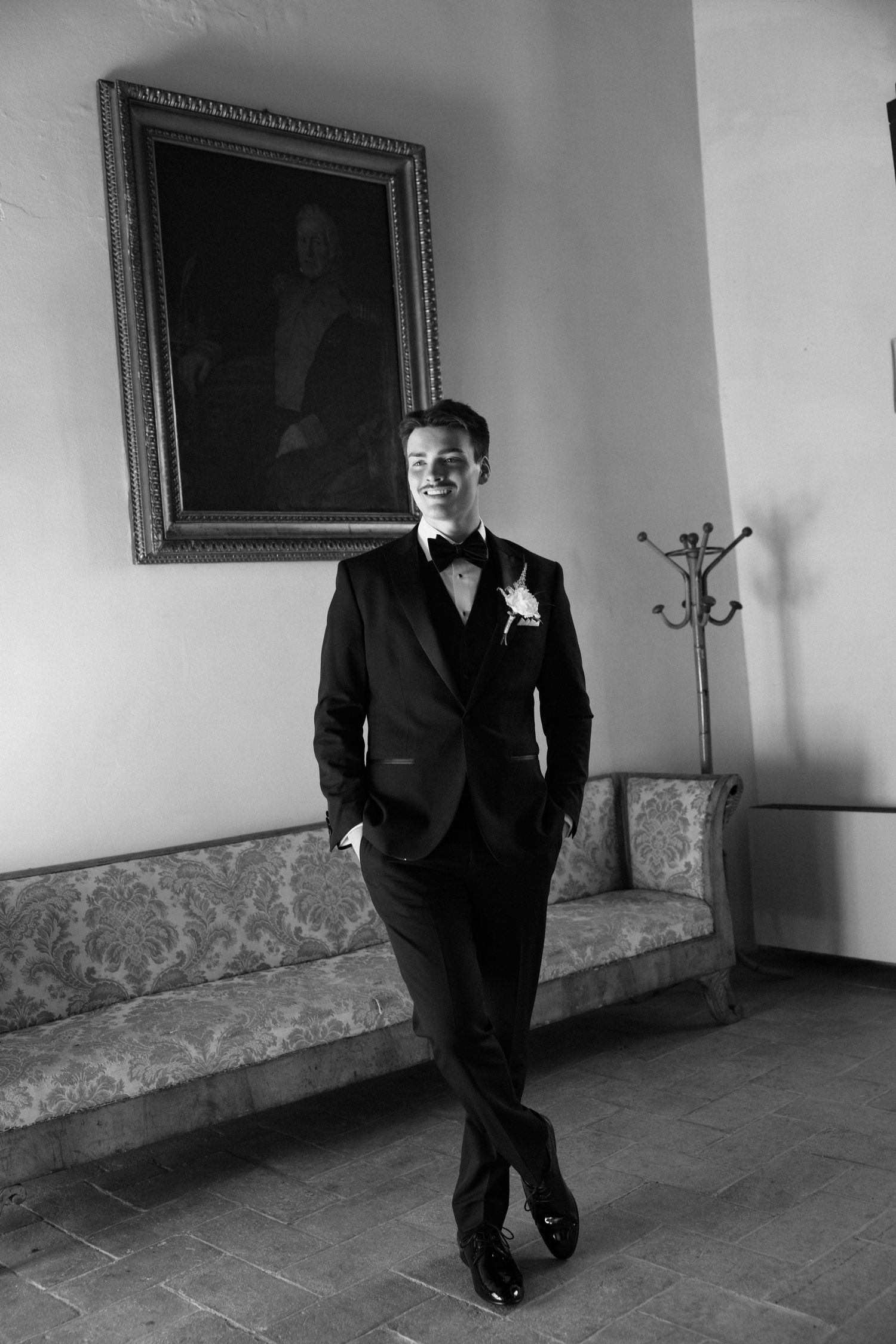 Black and white photo sequence showing a person in a tuxedo walking and laughing in an elegant hallway.