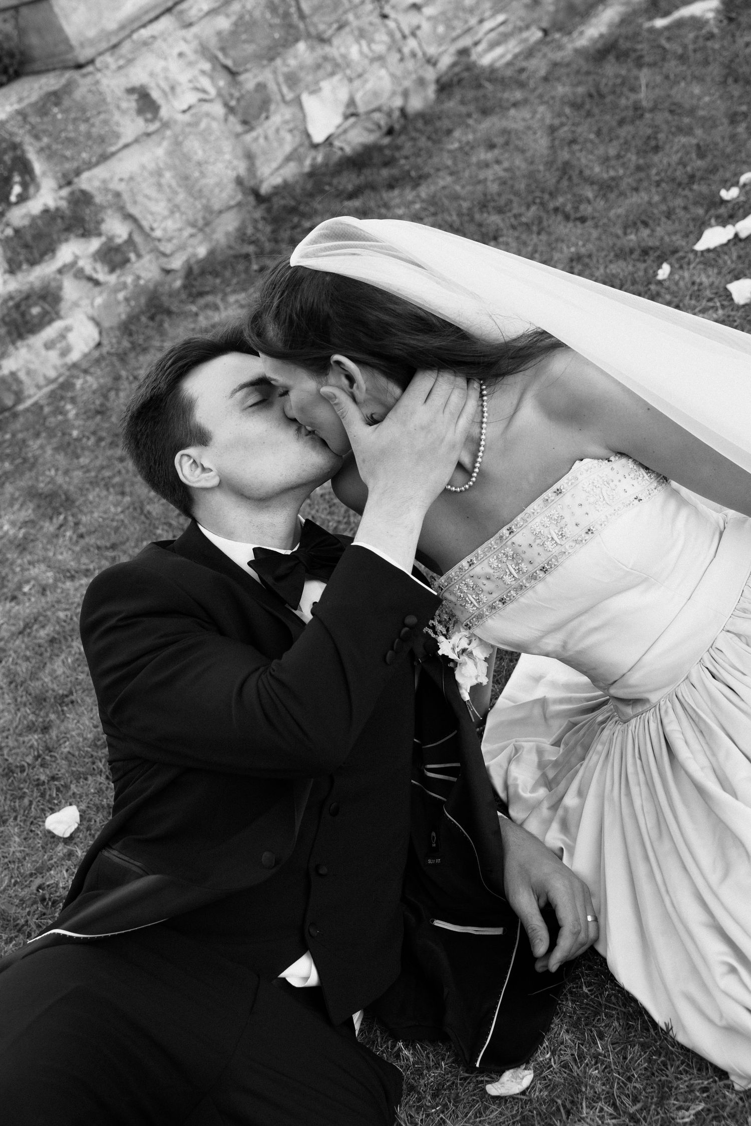 A black and white photo sequence shows a couple in wedding attire playfully dipping and posing on grass.