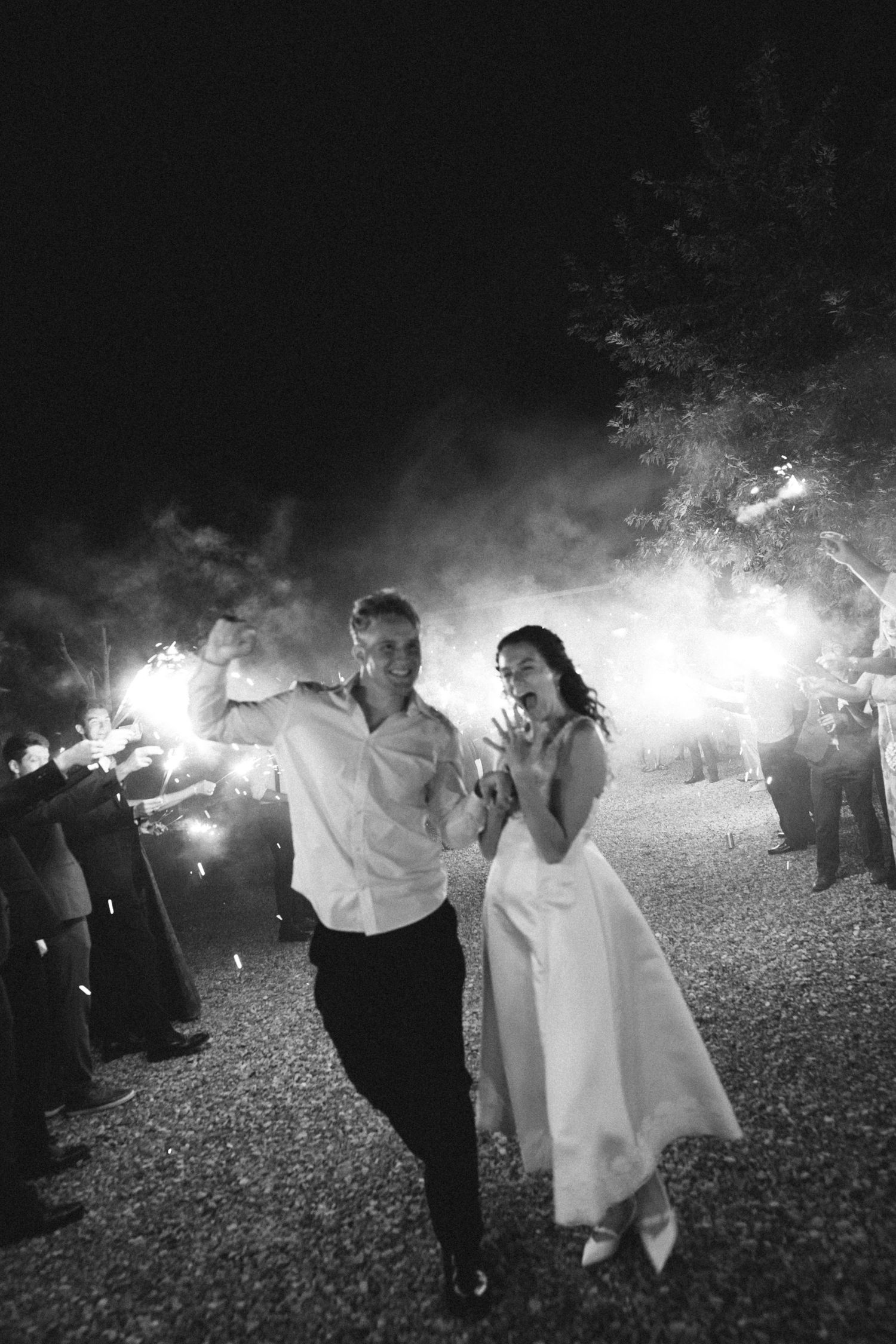 A couple dances together surrounded by sparklers creating a magical nighttime atmosphere at an outdoor celebration.