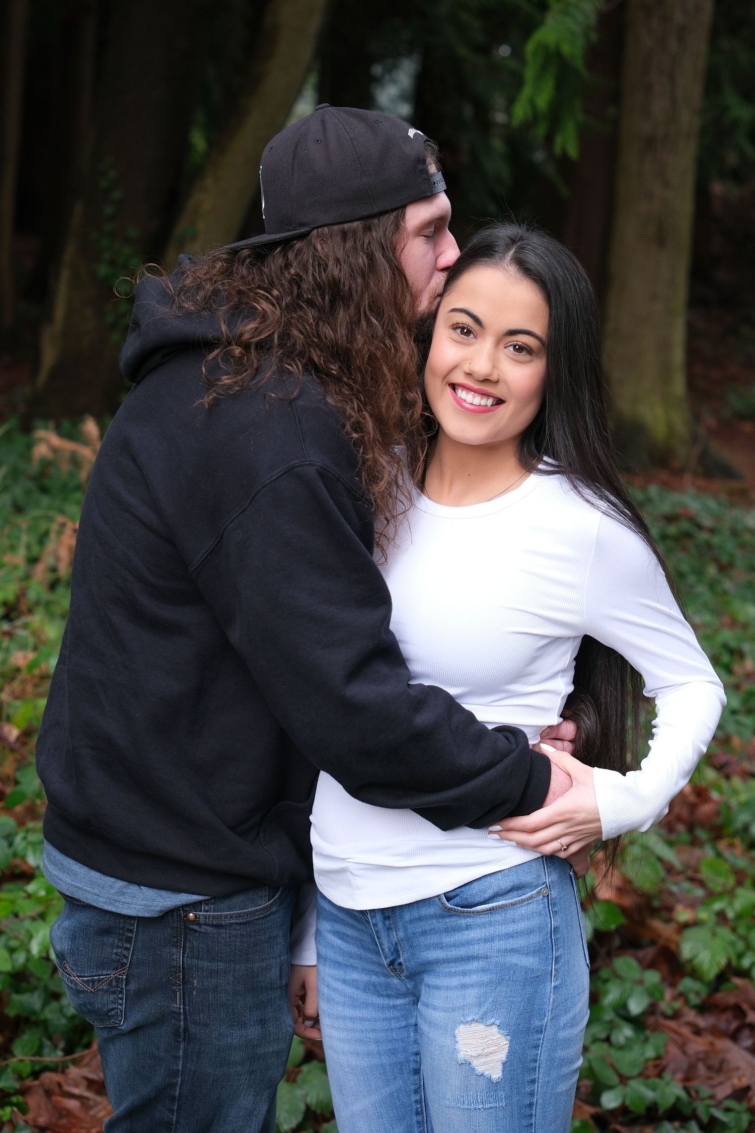 Photo of a couple with the one partner kissing the top of their partner's head