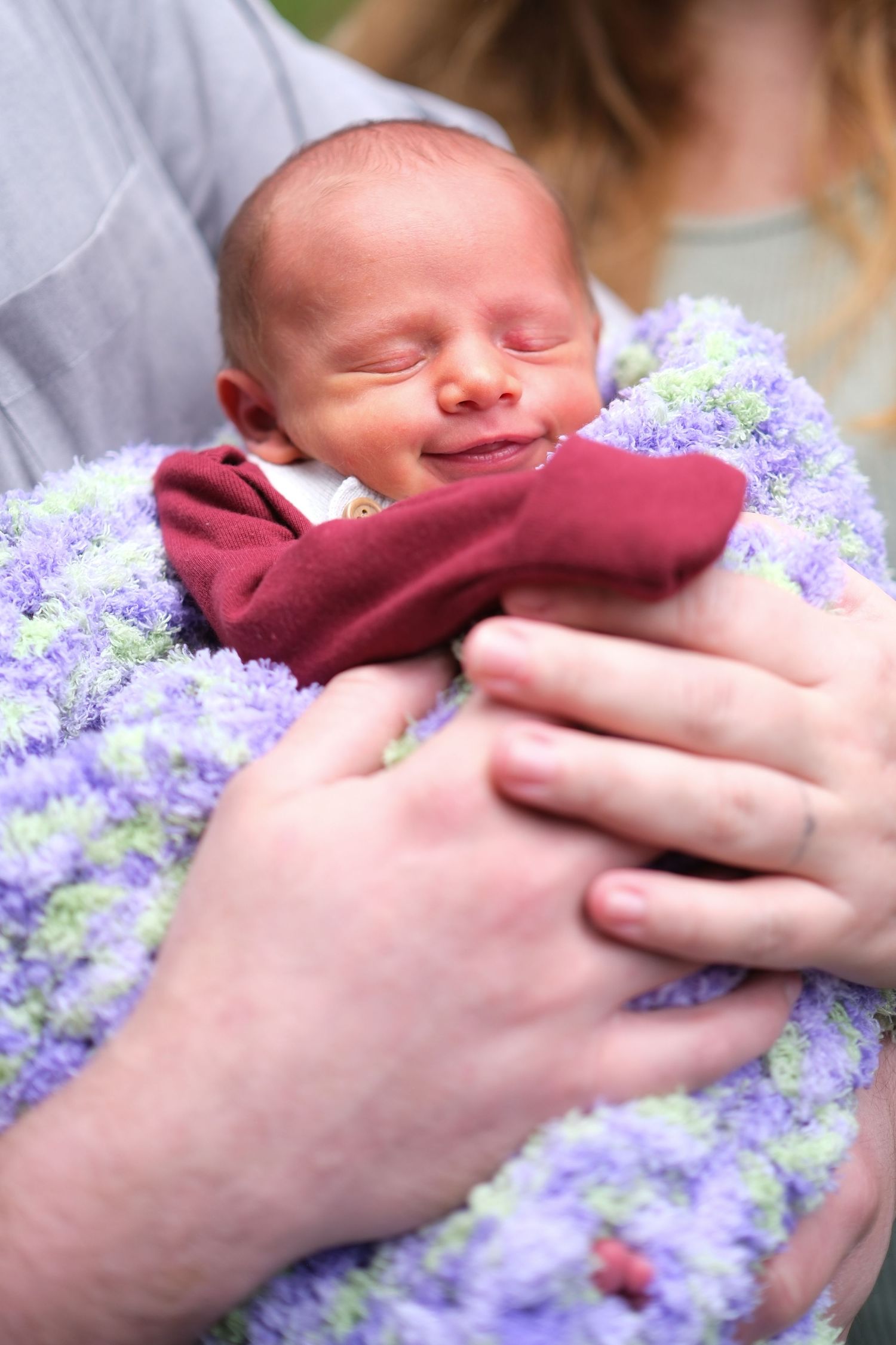 A baby snuggles in a fluffy purple blanket
