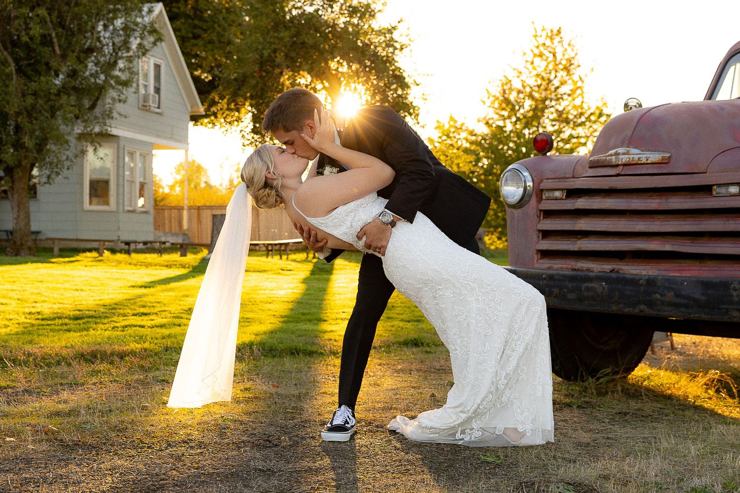 A dramatic dip pose captured at sunset with an antique truck and farmhouse in the background.