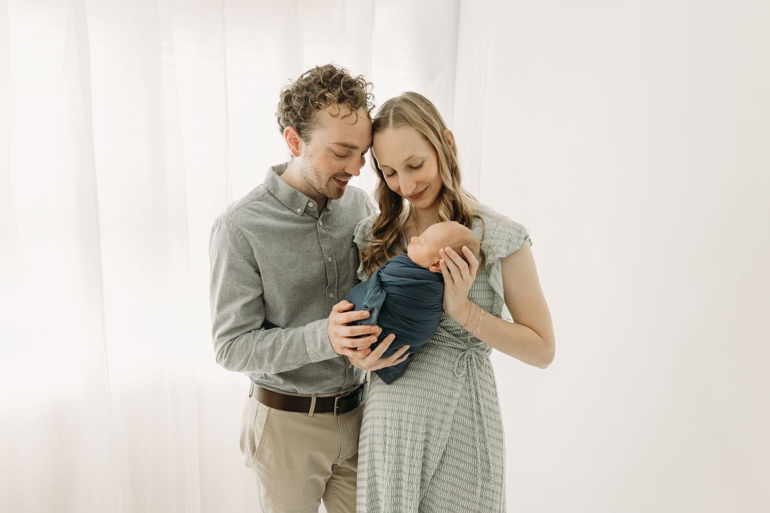 A couple in cozy neutral outfits shares tender moments together in three connected photos with white backdrops.