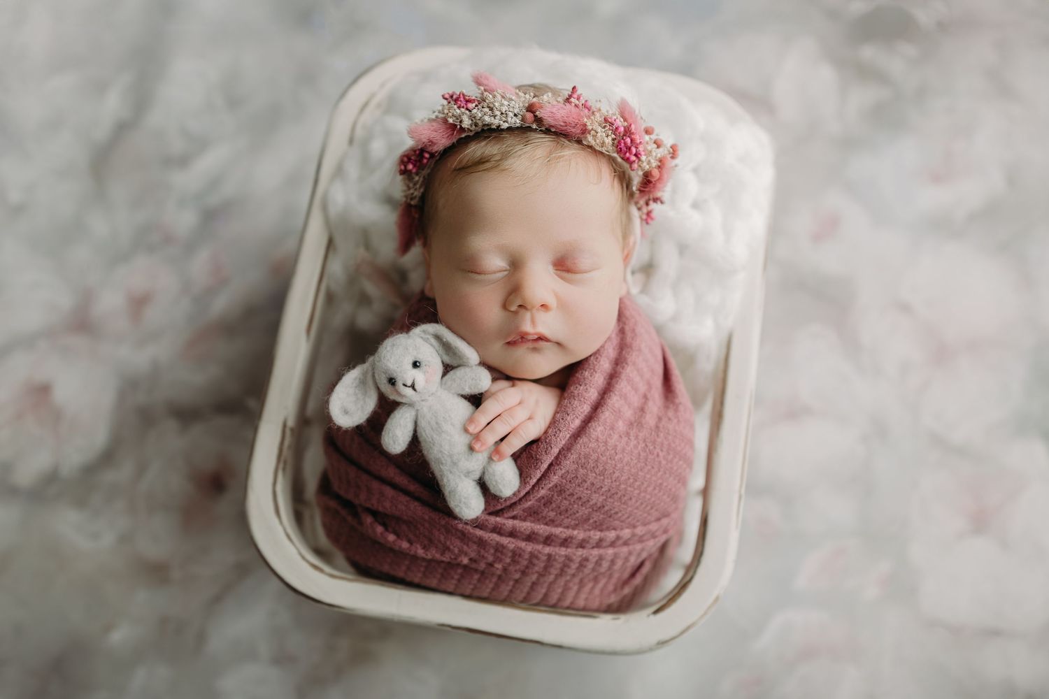 Sleeping baby with flower crown and stuffed bunny in rustic basket during newborn photoshoot in Tampa