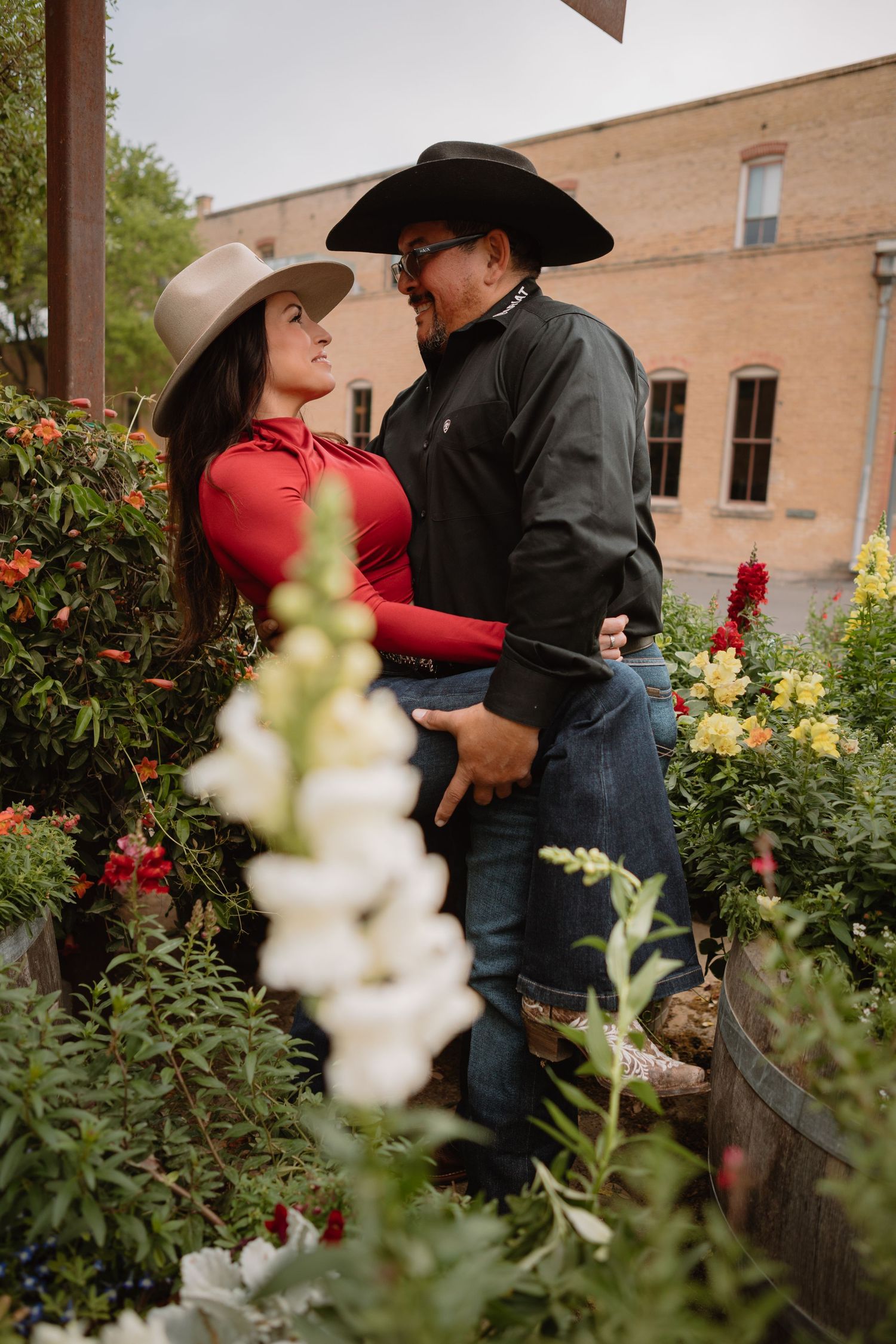 western couple in downtown Gruene Texas embracing within a circle of wildflowers growing in barrels