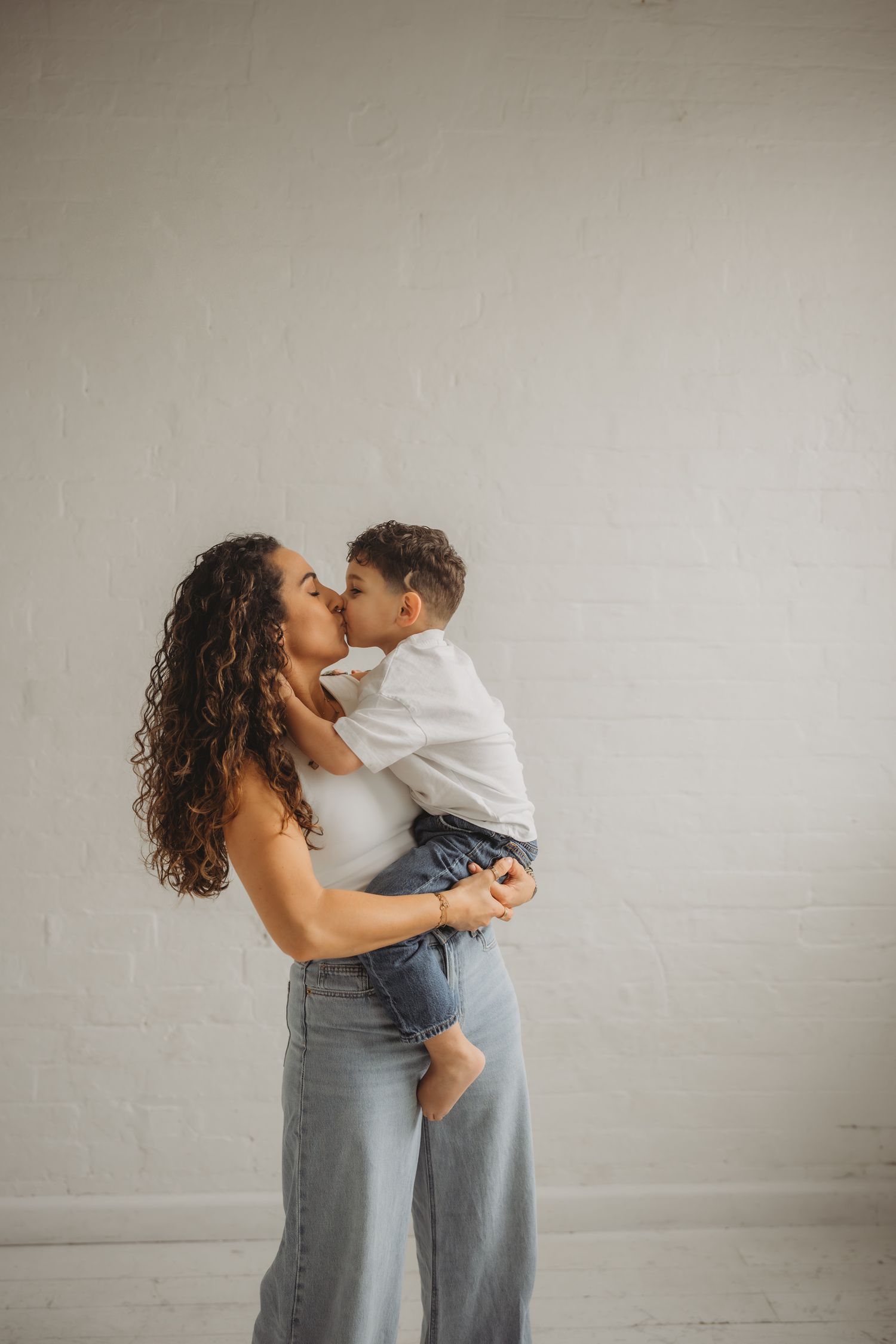A tender moment between parent and child against a neutral wall background.