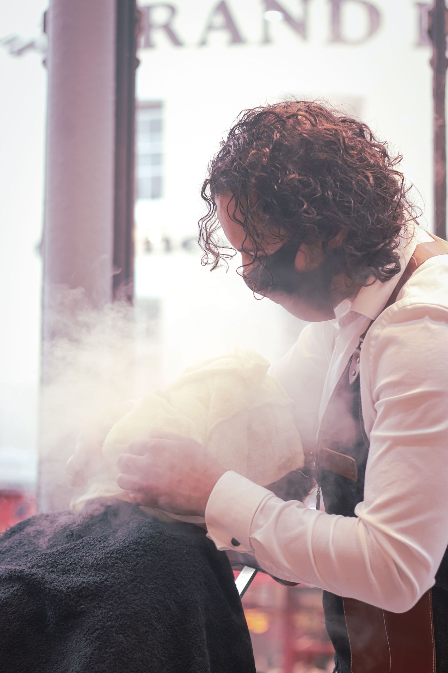 A person with curly hair wearing a white blazer leans forward in a sequence of progressive motion shots.