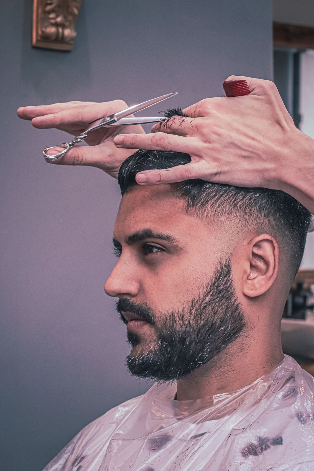 Side profile sequence showing a barber using clippers to give a precise haircut with a fade technique.