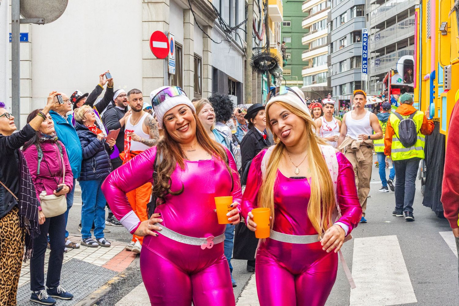 A group of dancers in bright pink costumes perform together during a street festival celebration.