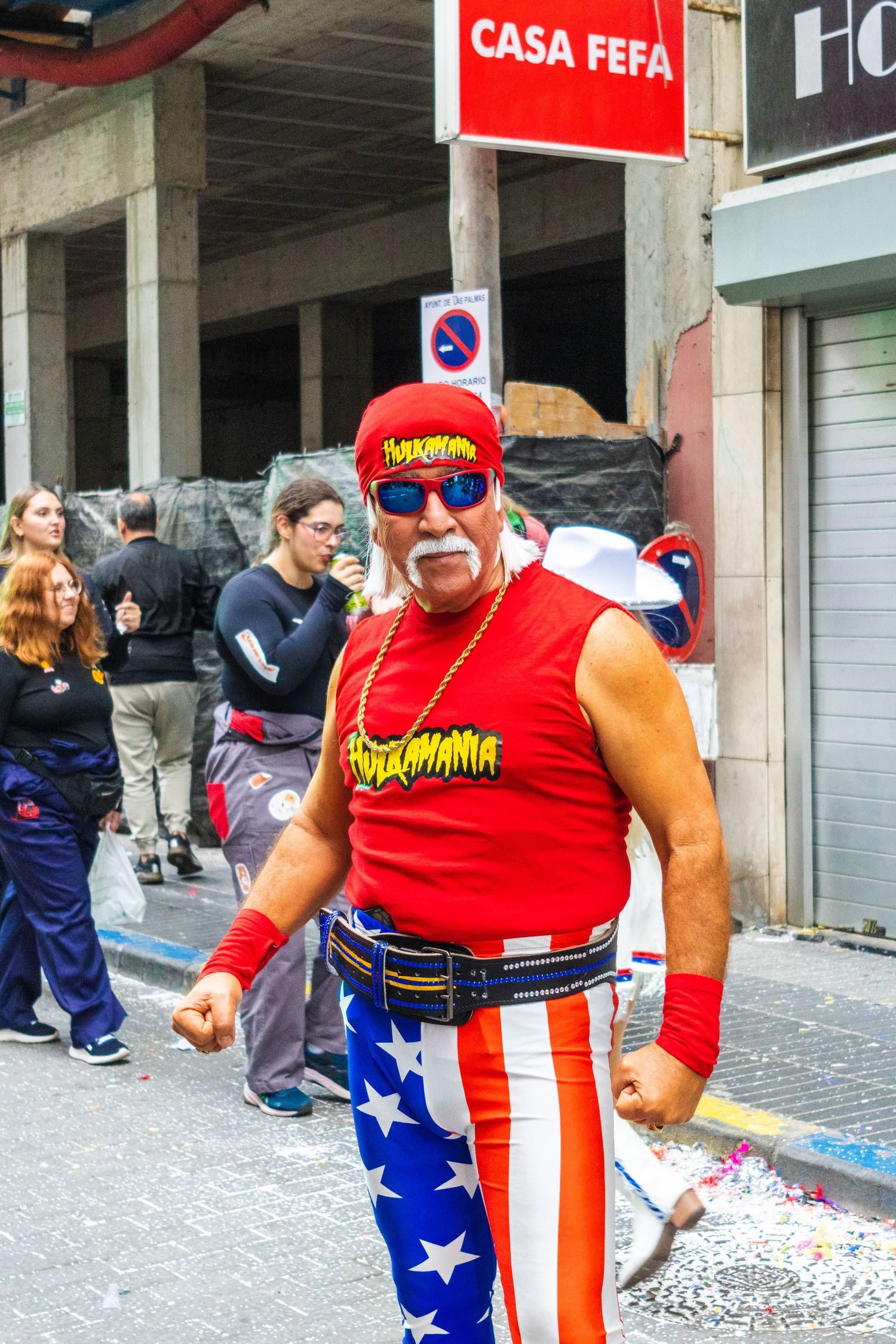 Person in red shirt and American flag pants stands on a city street near a storefront with Casa Fefa signage.