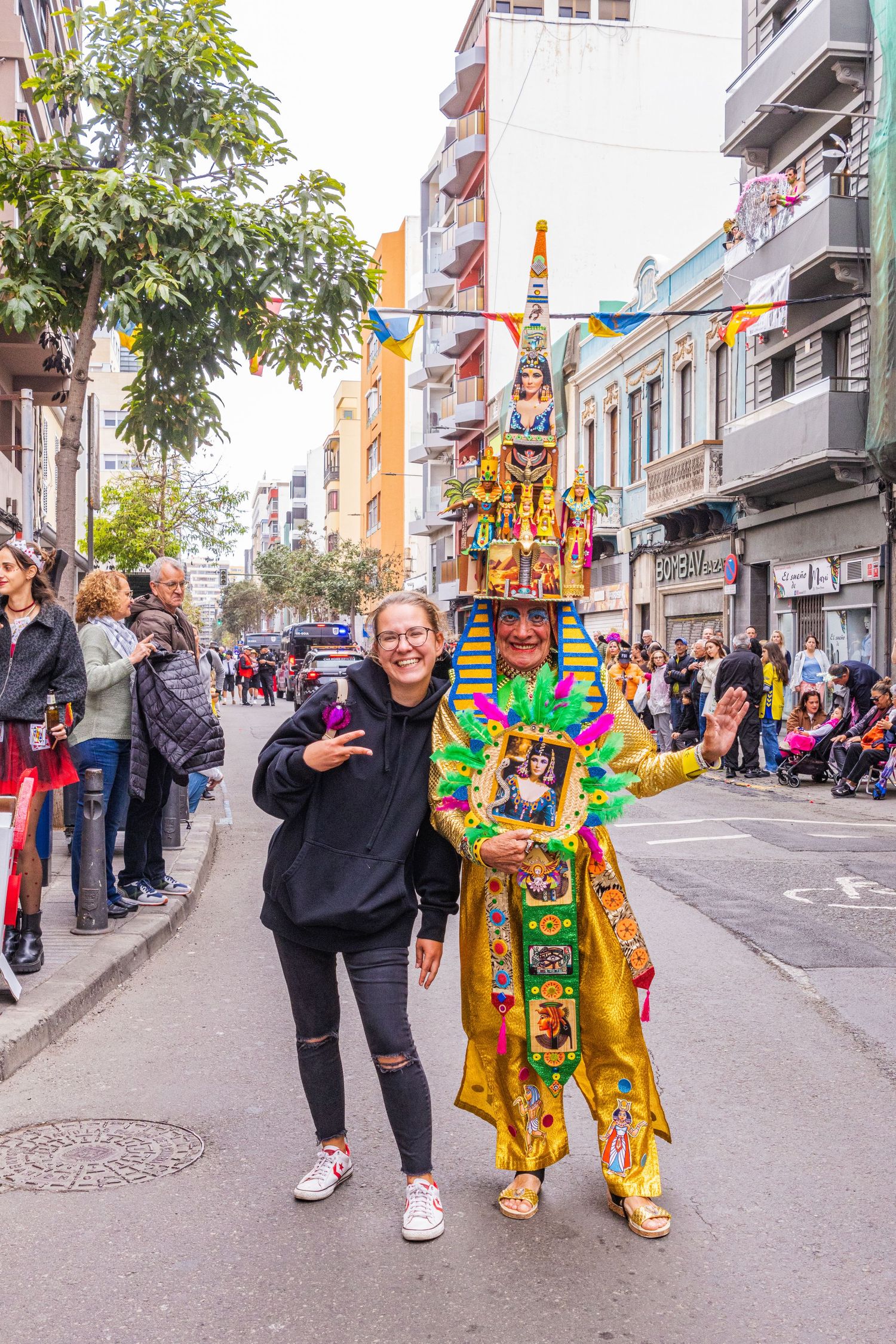 People celebrating in a vibrant city street with someone wearing a colorful costume during a festive event.