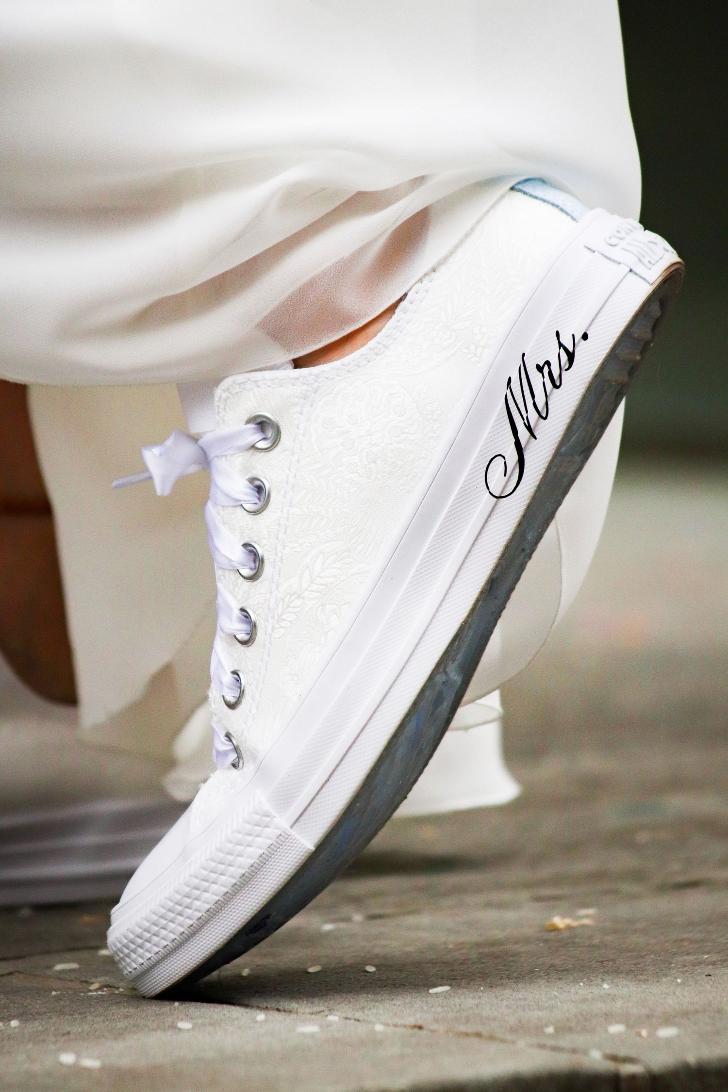 A sequence of white sneakers in motion showing progressive steps on a concrete surface.