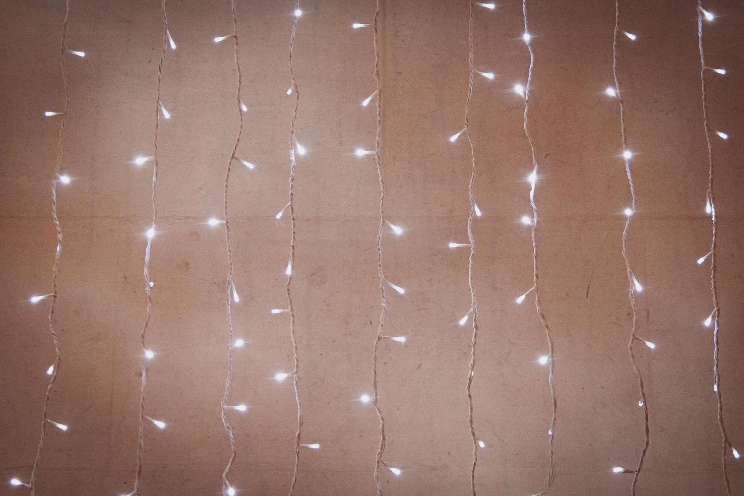String lights create a magical curtain of warm white illumination against a dark brown background.