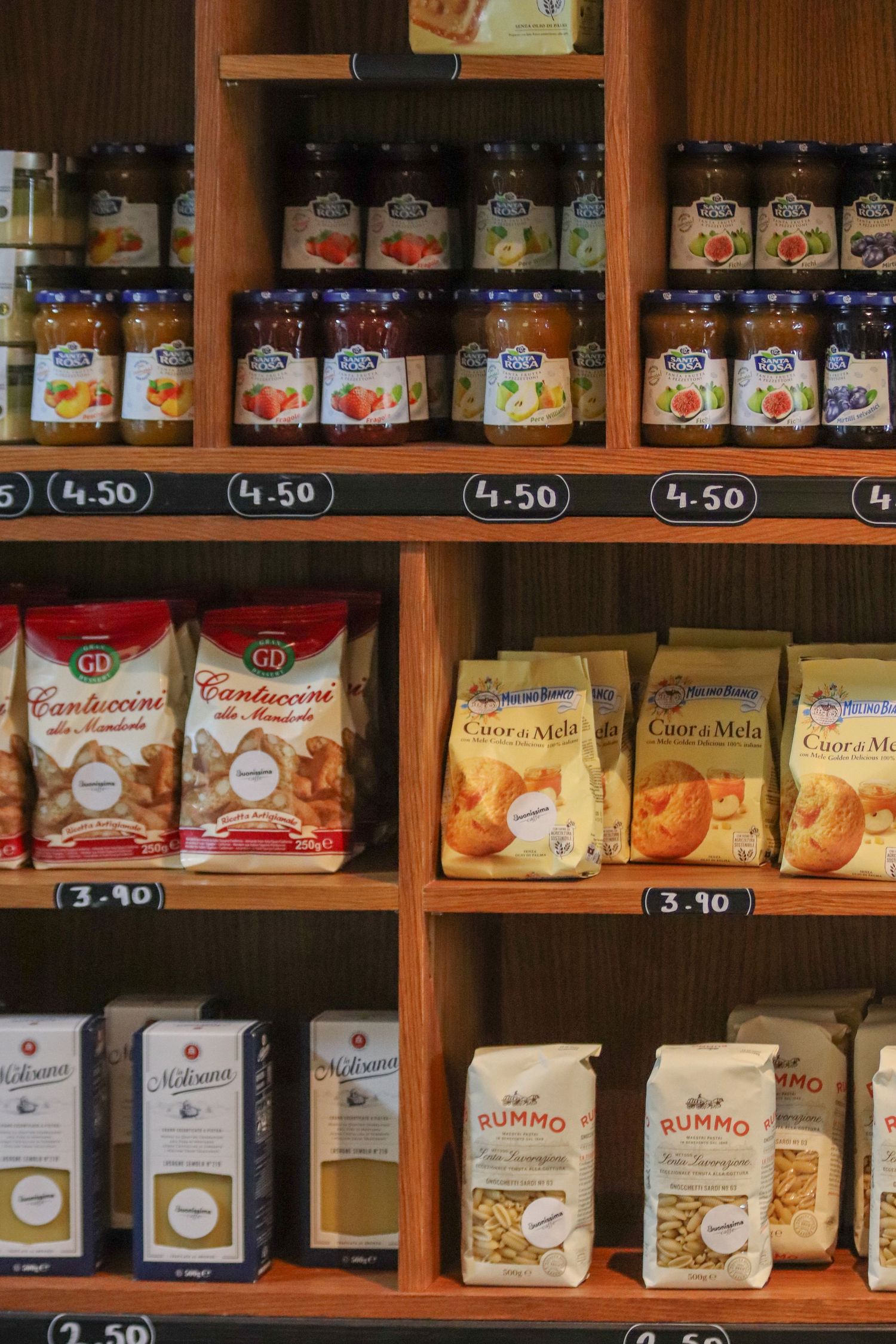 Wooden shelves stocked with glass jars and packaged food items in a specialty grocery store.